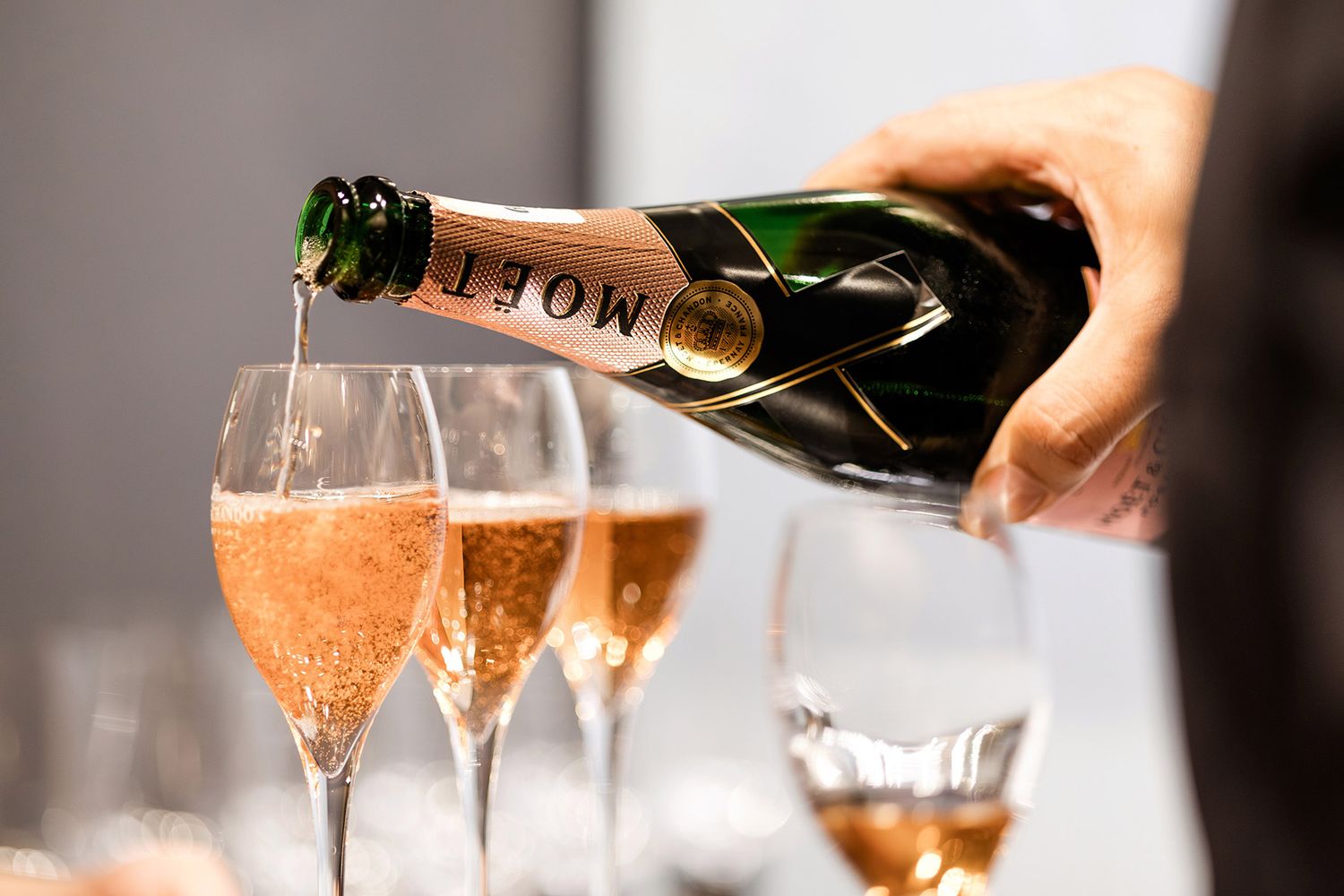 A close-up detail shot of premium Moët & Chandon champagne being poured into elegant glass flutes at a luxury VIP corporate reception.
