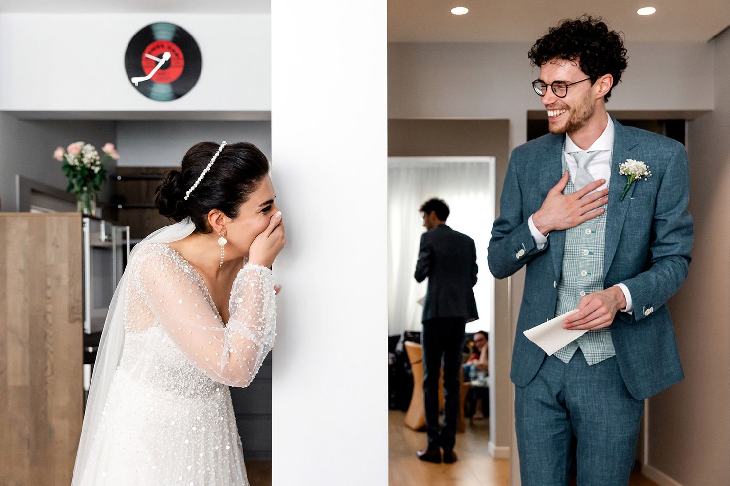A German groom holds his hand over his heart while the Persian bride laughs, emotional first look inside an Istanbul apartment.