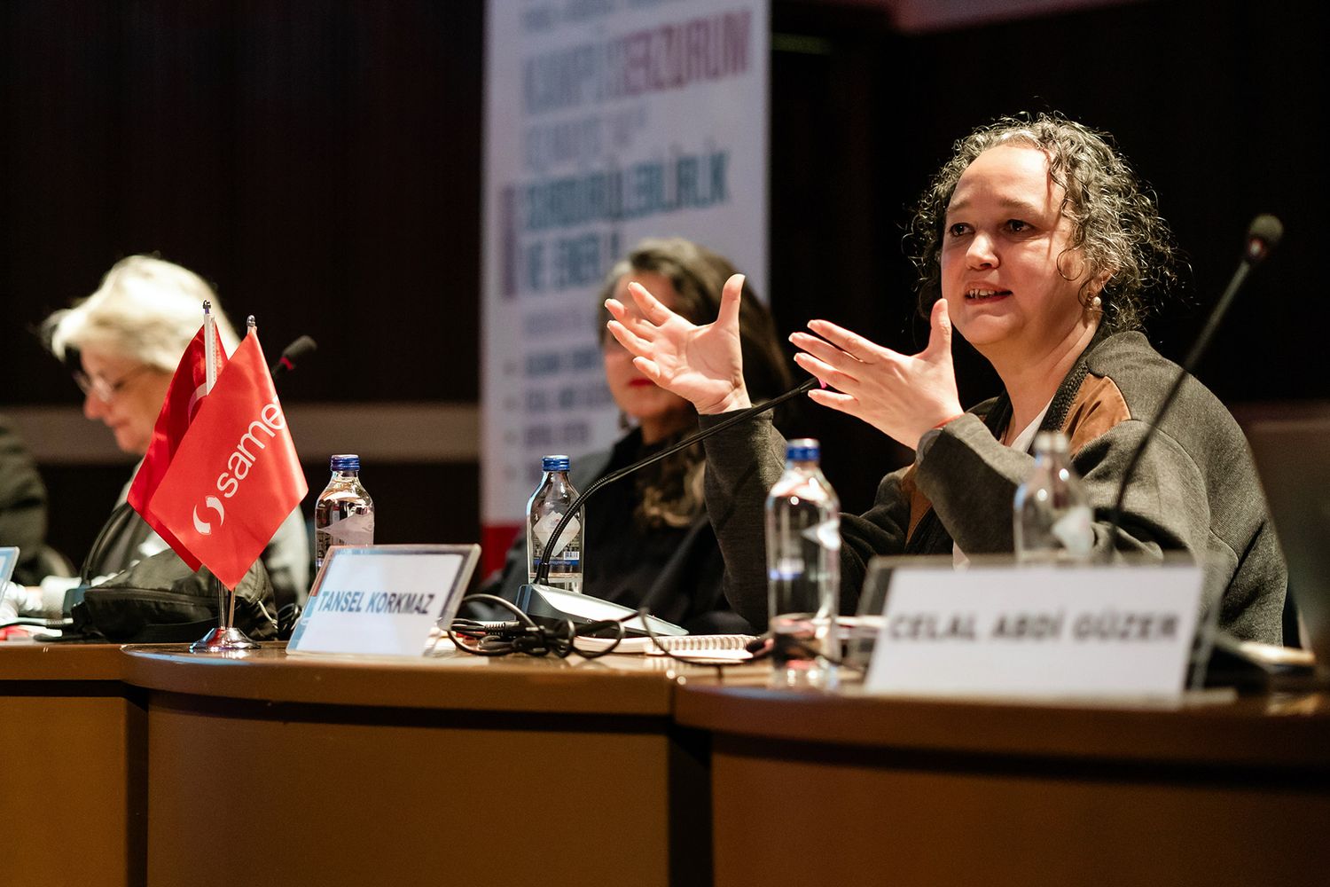 A female industry expert speaking passionately at a branded Samet panel discussion during a professional corporate conference.