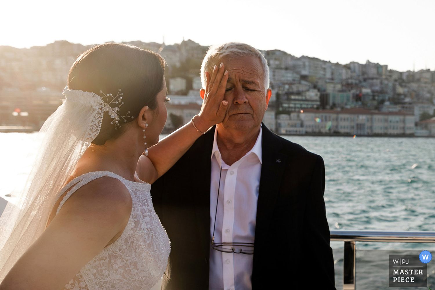 WPJA award-winning emotional photo of a bride tenderly touching her father's face during a wedding on a Bosphorus boat in Istanbul.