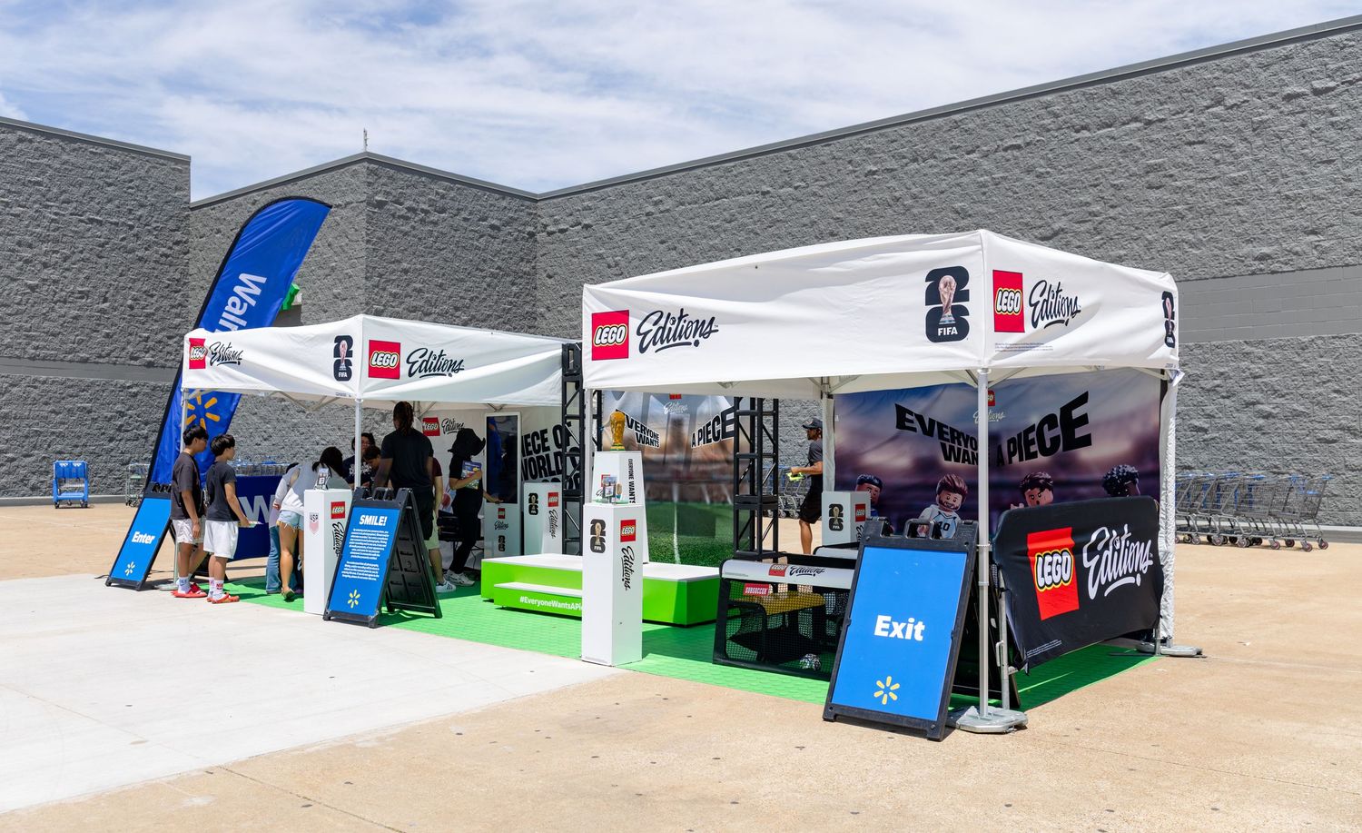 LEGO Editions and Walmart co-branded outdoor event booth setup against a gray building exterior.