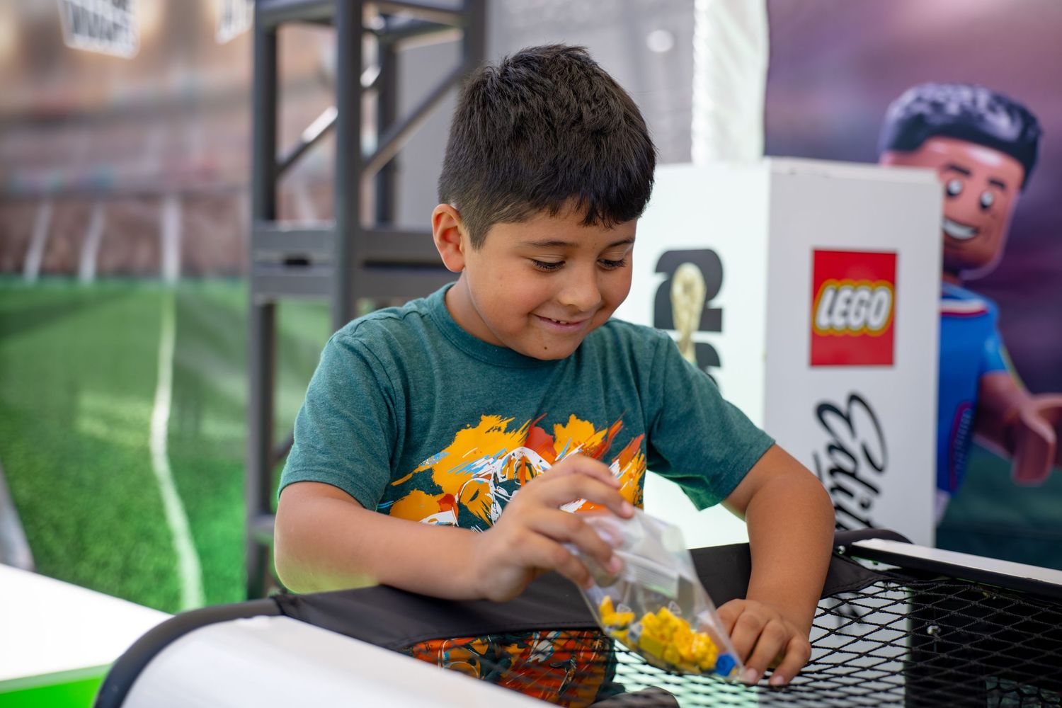 A young boy smiles while playing with LEGO bricks at an interactive LEGO Editions event.