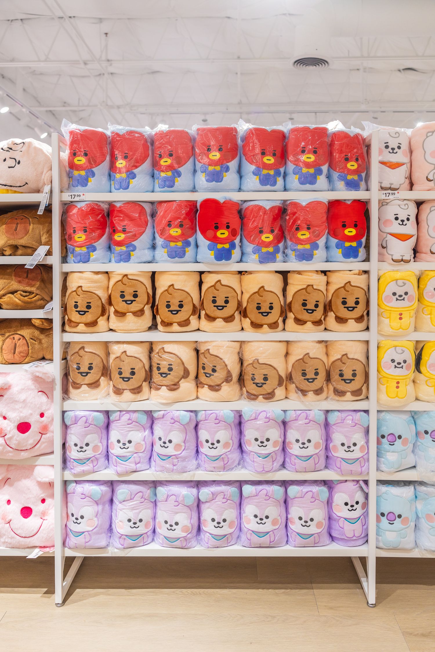 Shelves filled with colorful BT21 character plush blankets neatly arranged in a retail store.