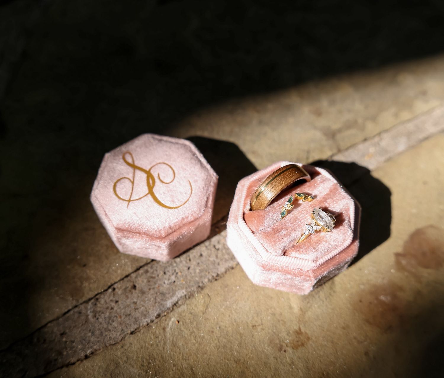 Diamond engagement ring and gold wedding band displayed in an octagonal pink velvet ring box.