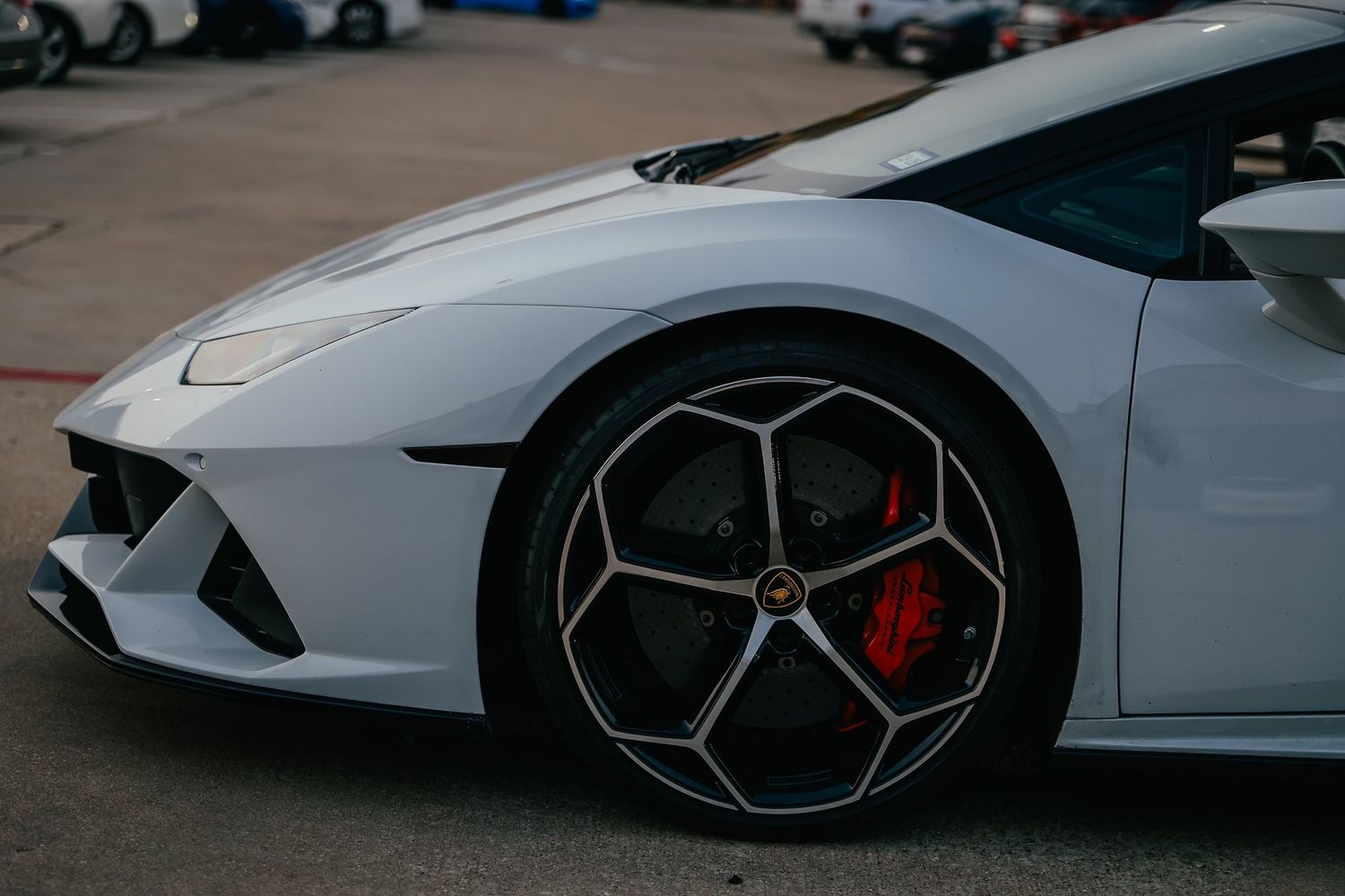 White Lamborghini sports car with geometric alloy wheels and red brake calipers closeup.