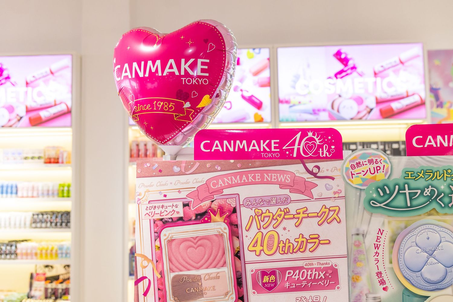 CANMAKE Tokyo 40th anniversary display featuring a pink heart balloon and powder blush cosmetic products.