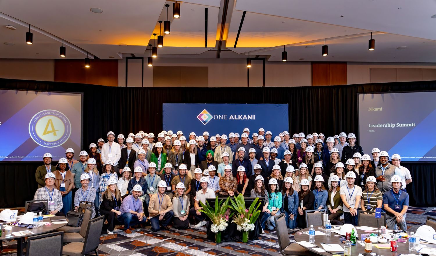 Large group of employees wearing hard hats pose together at One Alkane Leadership Summit conference event.