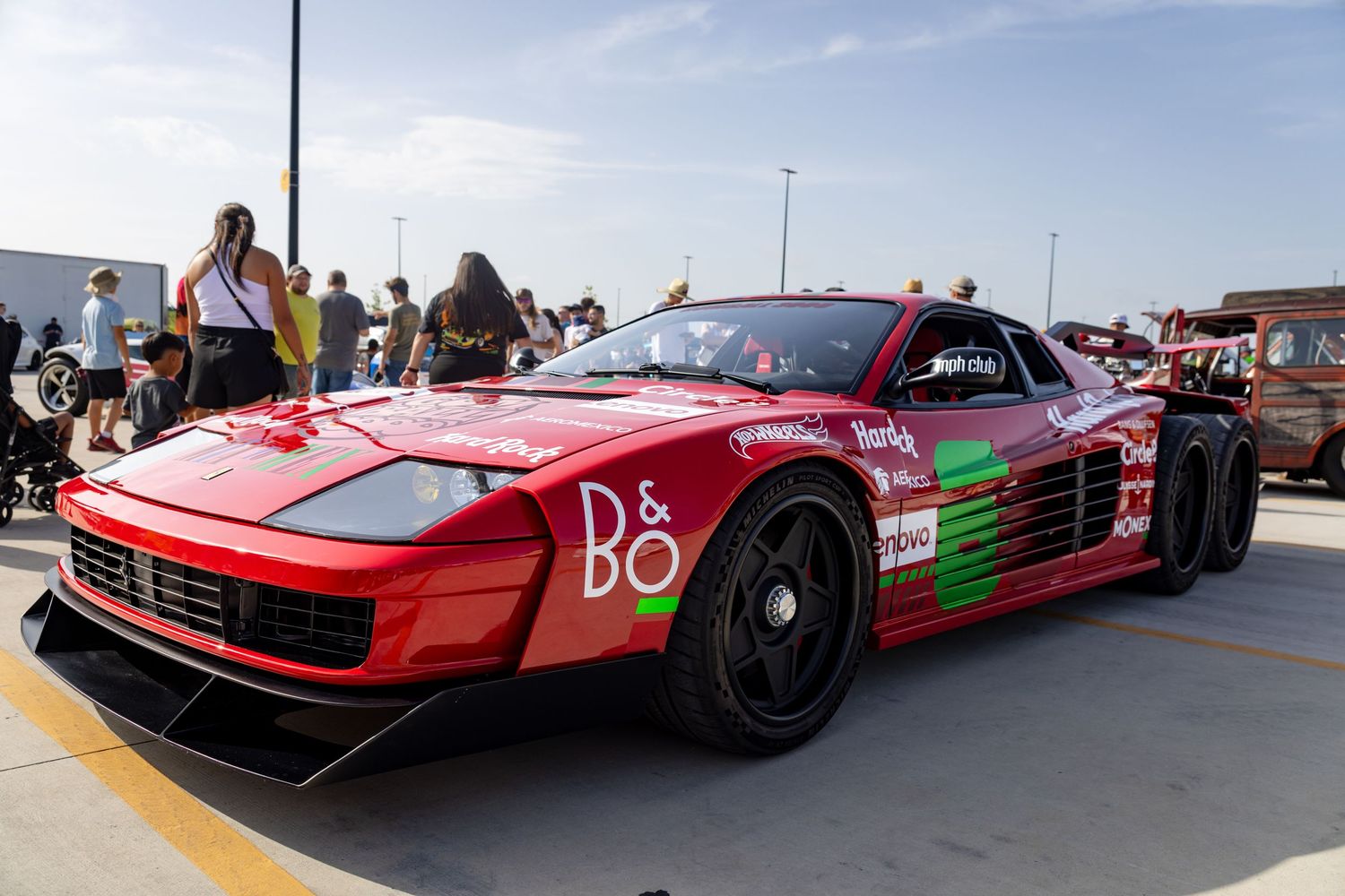 Red Ferrari Testarossa race car with B&O branding on display at an outdoor automotive event.