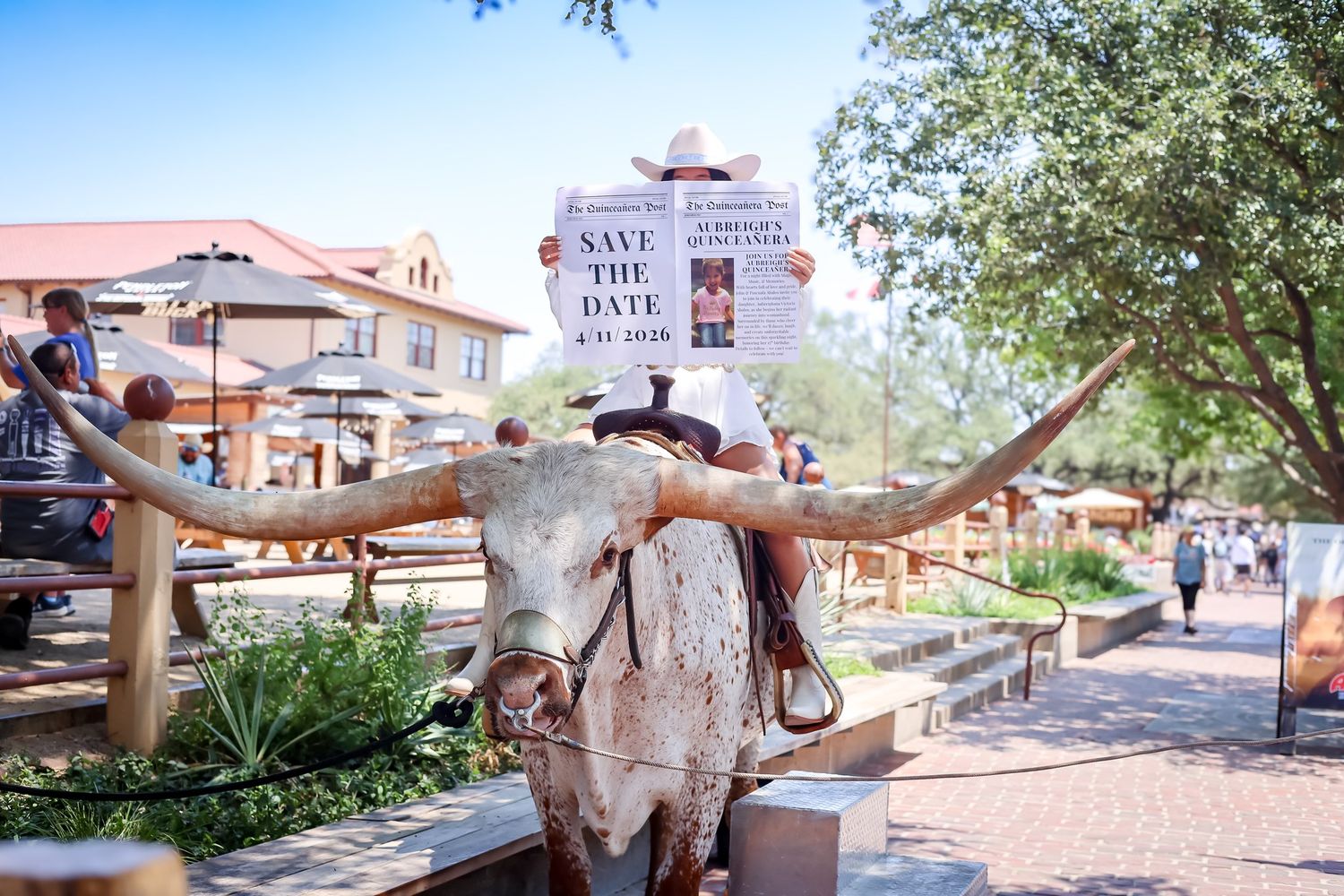 Longhorn skull statue with Save the Date Quinceanera newspaper sign in outdoor market setting.