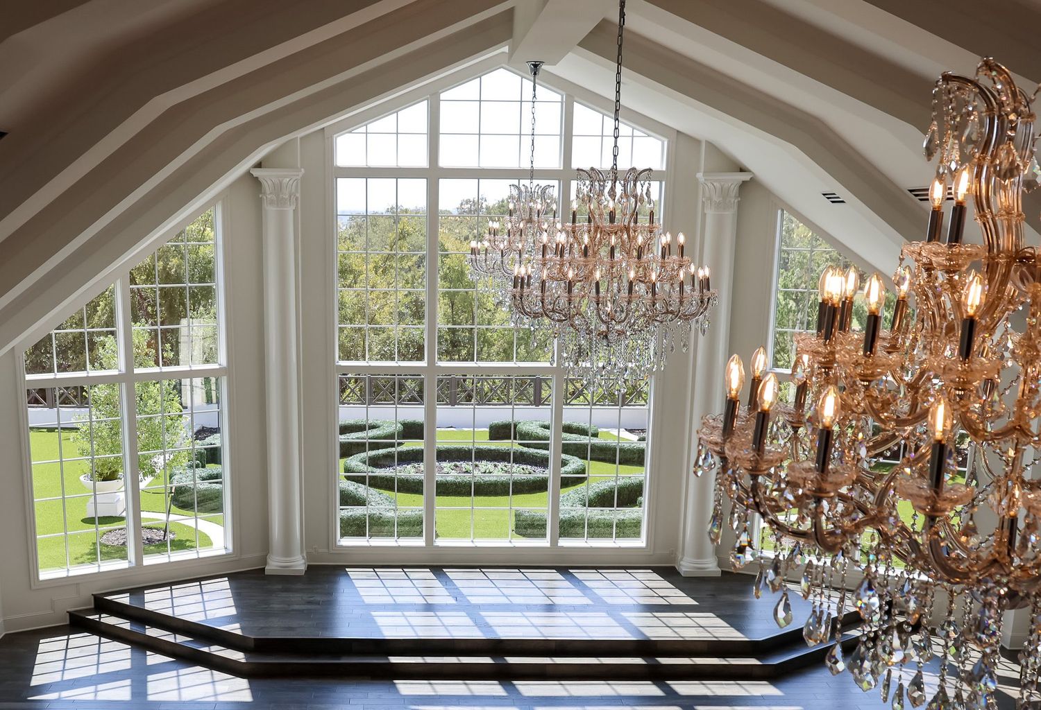 Stunning venue interior with vaulted windows, rose gold chandeliers, and garden views.
