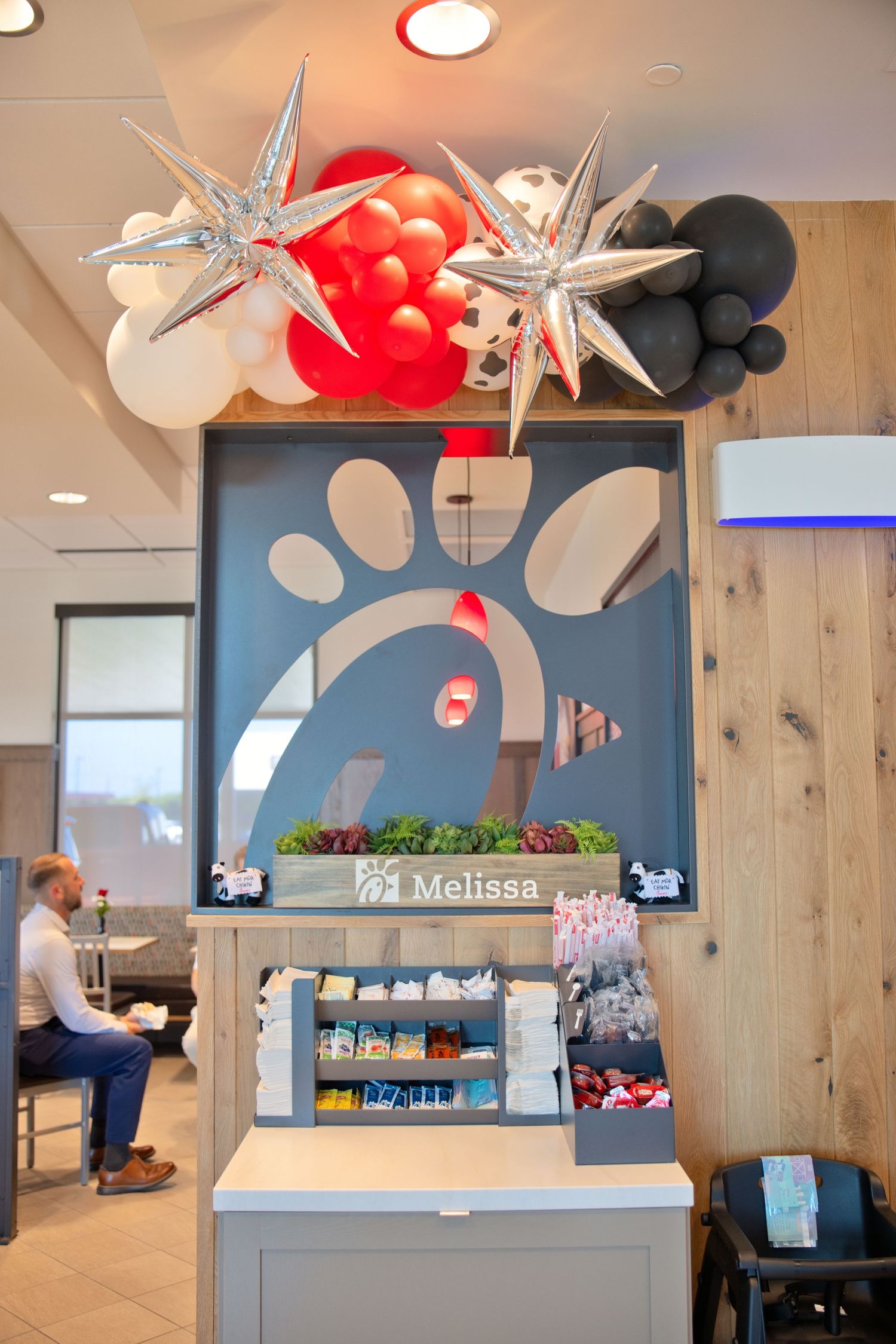 Chick-fil-A interior counter decorated with colorful balloons and star decorations for grand opening.