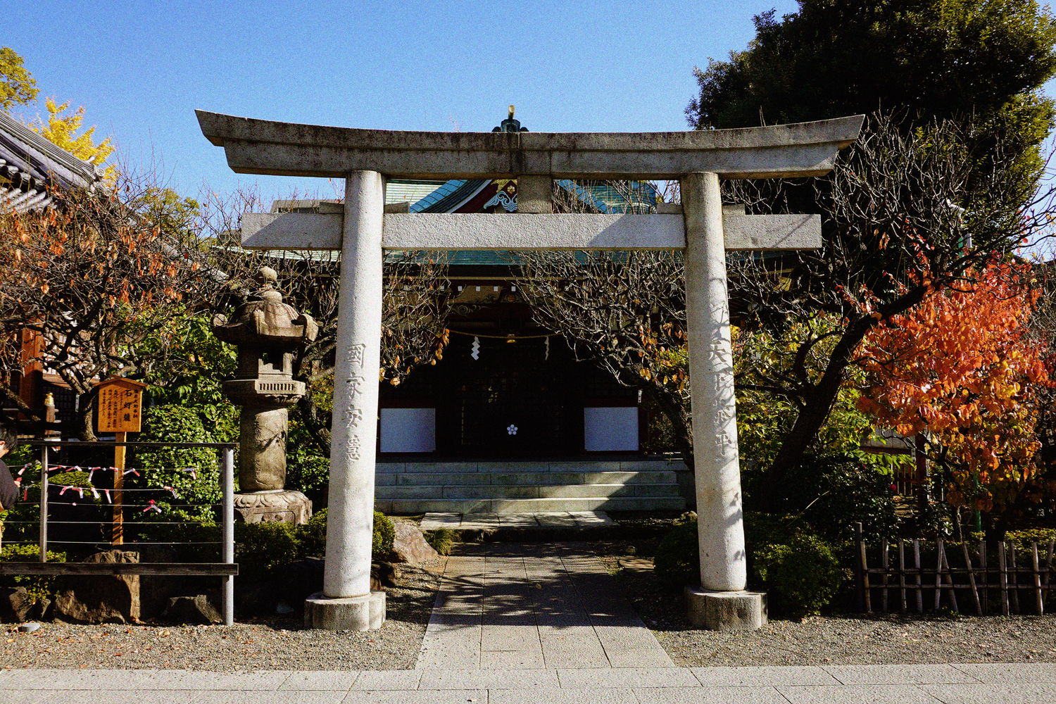 Traditional Japanese stone torii gate at a shrine entrance surrounded by autumn foliage.