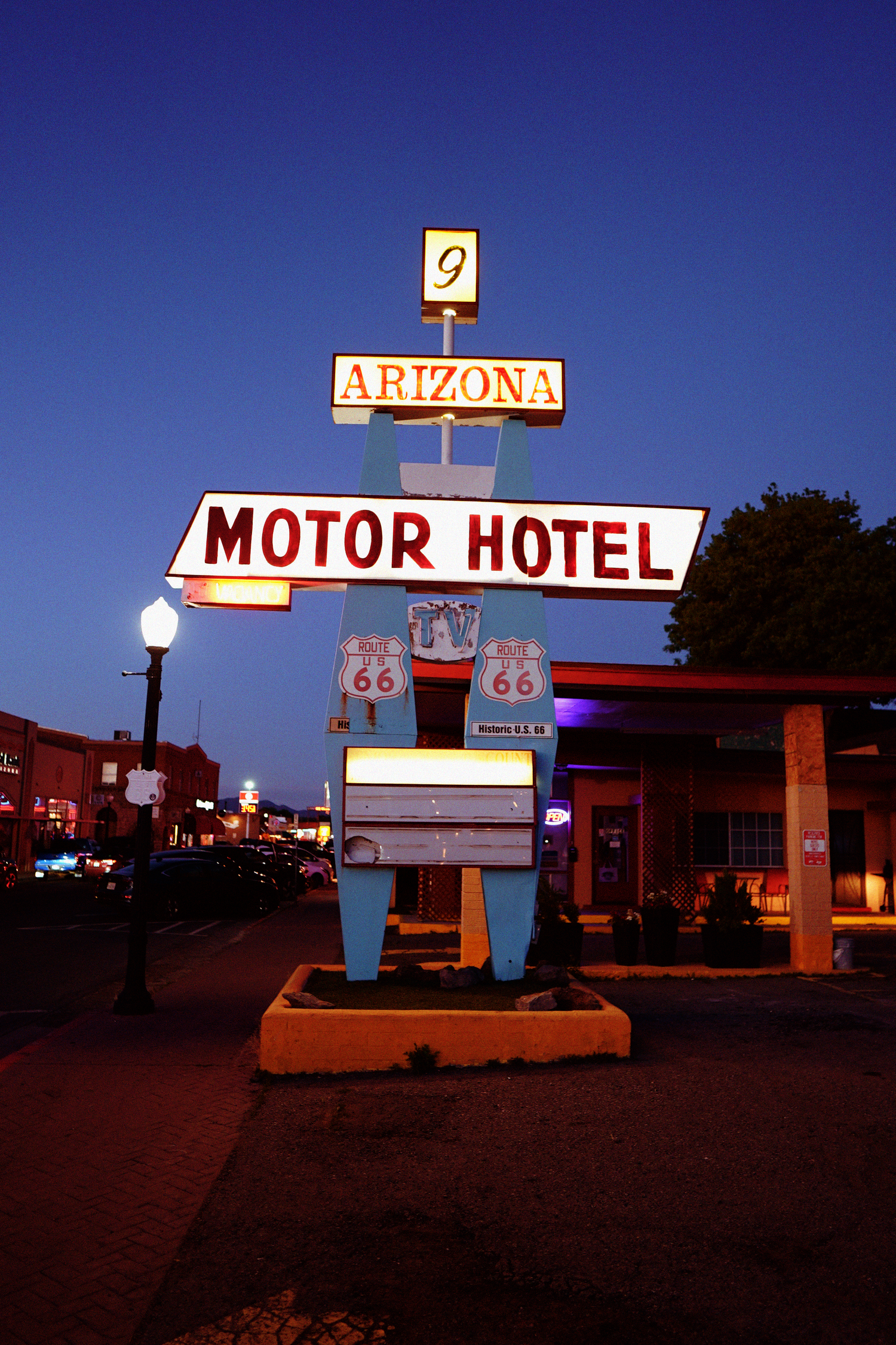 Iconic neon Route 66 Arizona Motor Hotel sign glowing against deep blue twilight sky.