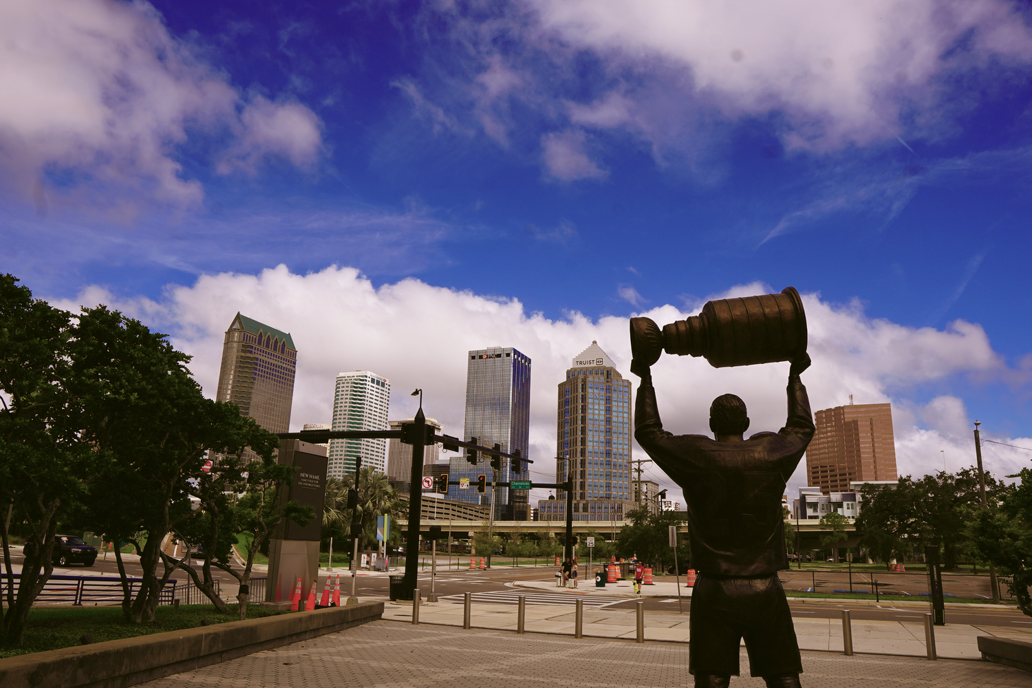 A silhouette of a hockey player statue holding the Stanley Cup trophy with Tampa skyline in background.