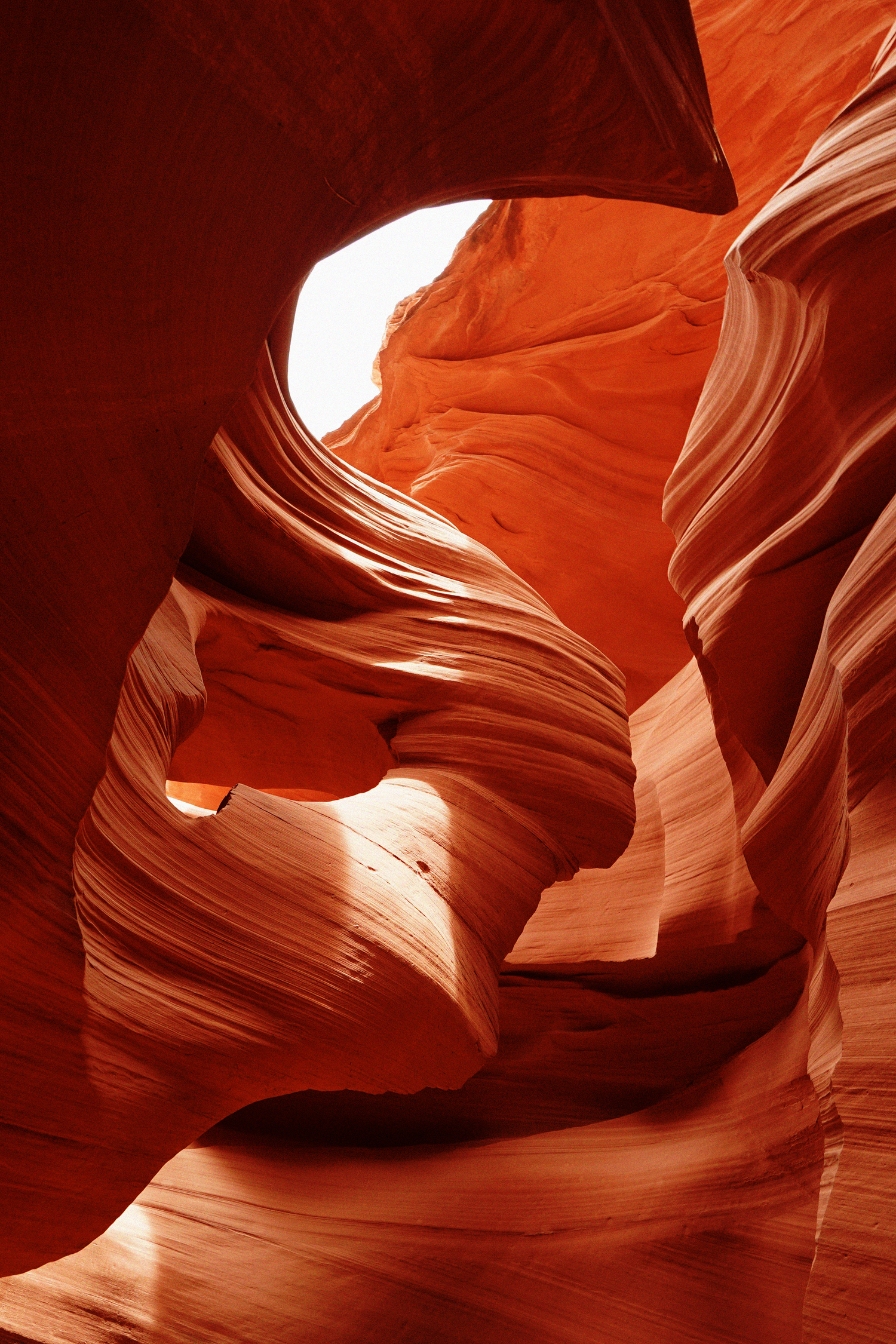 Stunning red sandstone walls of Antelope Canyon slot canyon with flowing wave-like formations and light beam from above.