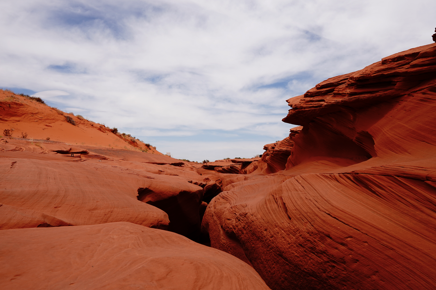 Dramatic red sandstone rock formations under cloudy blue sky in Arizona desert landscape.