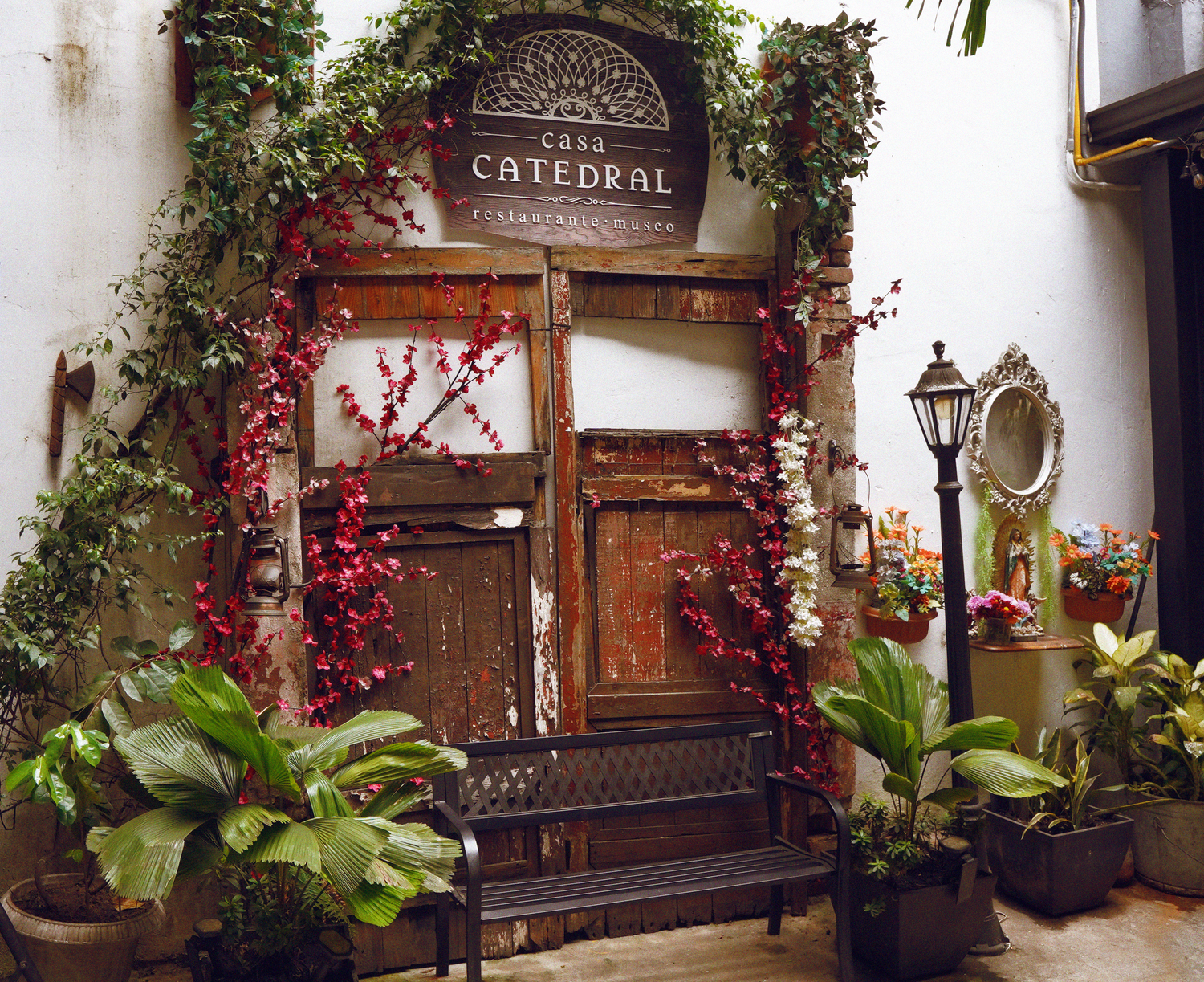 Casa Catedral restaurant entrance adorned with lush plants and decorative red floral vines.