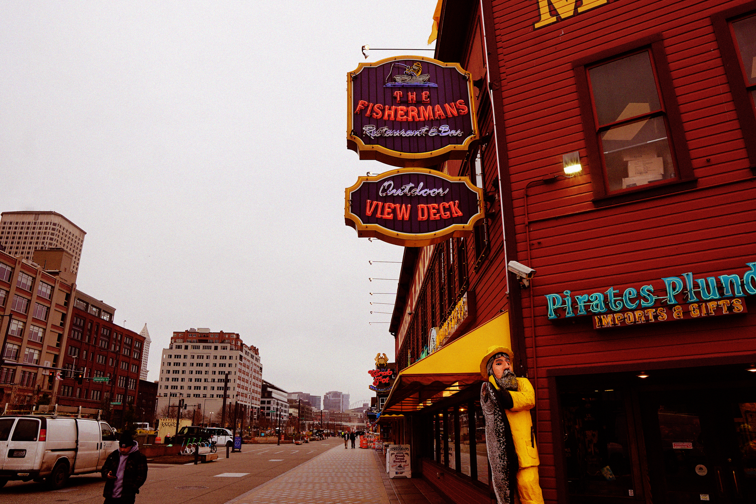 The Fishermans restaurant sign and Pirates Plunder shop on a rainy waterfront street.