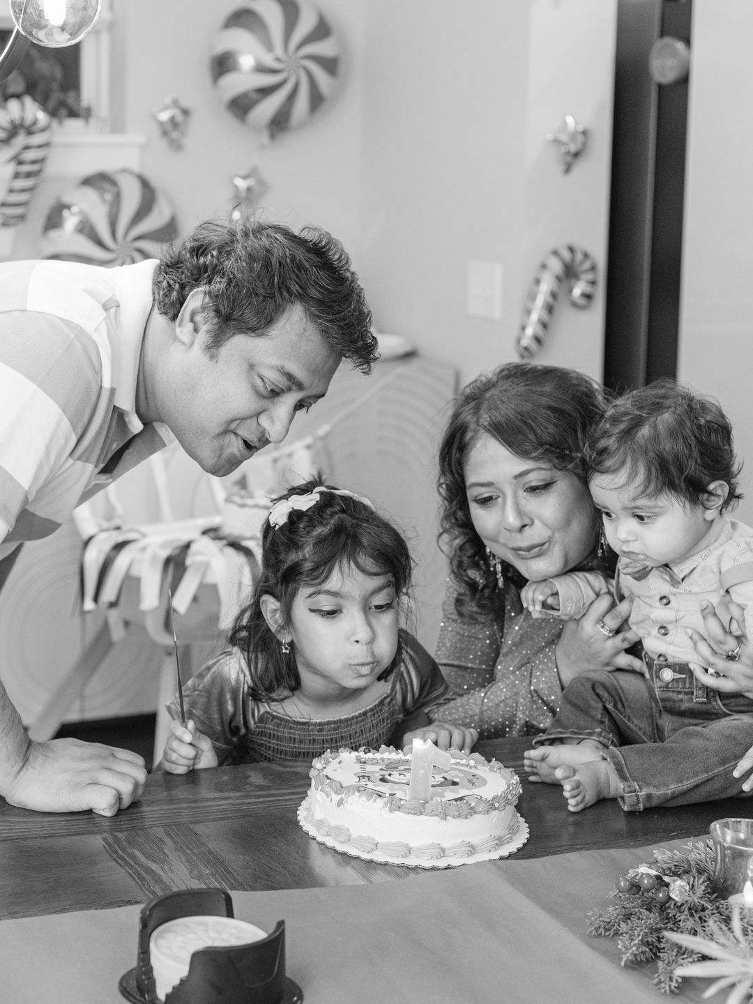 Black and white photo of people blowing out candles on a birthday cake.