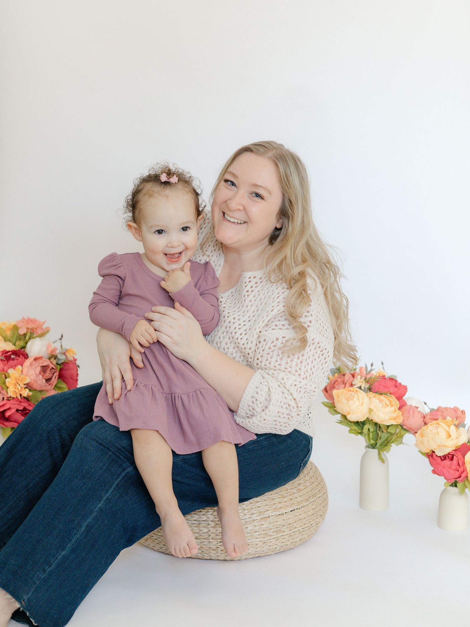 Mother and child share tender moments against white backdrop with colorful flowers.