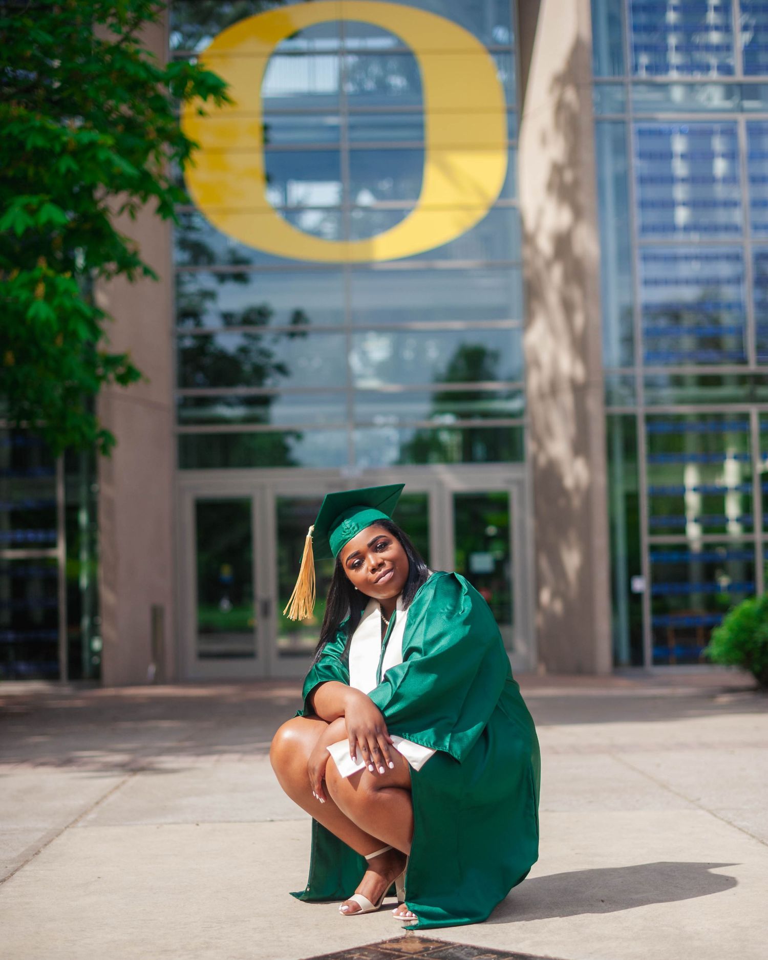 Senior portrait crouching near University of Oregon O logo — school spirit graduation photos