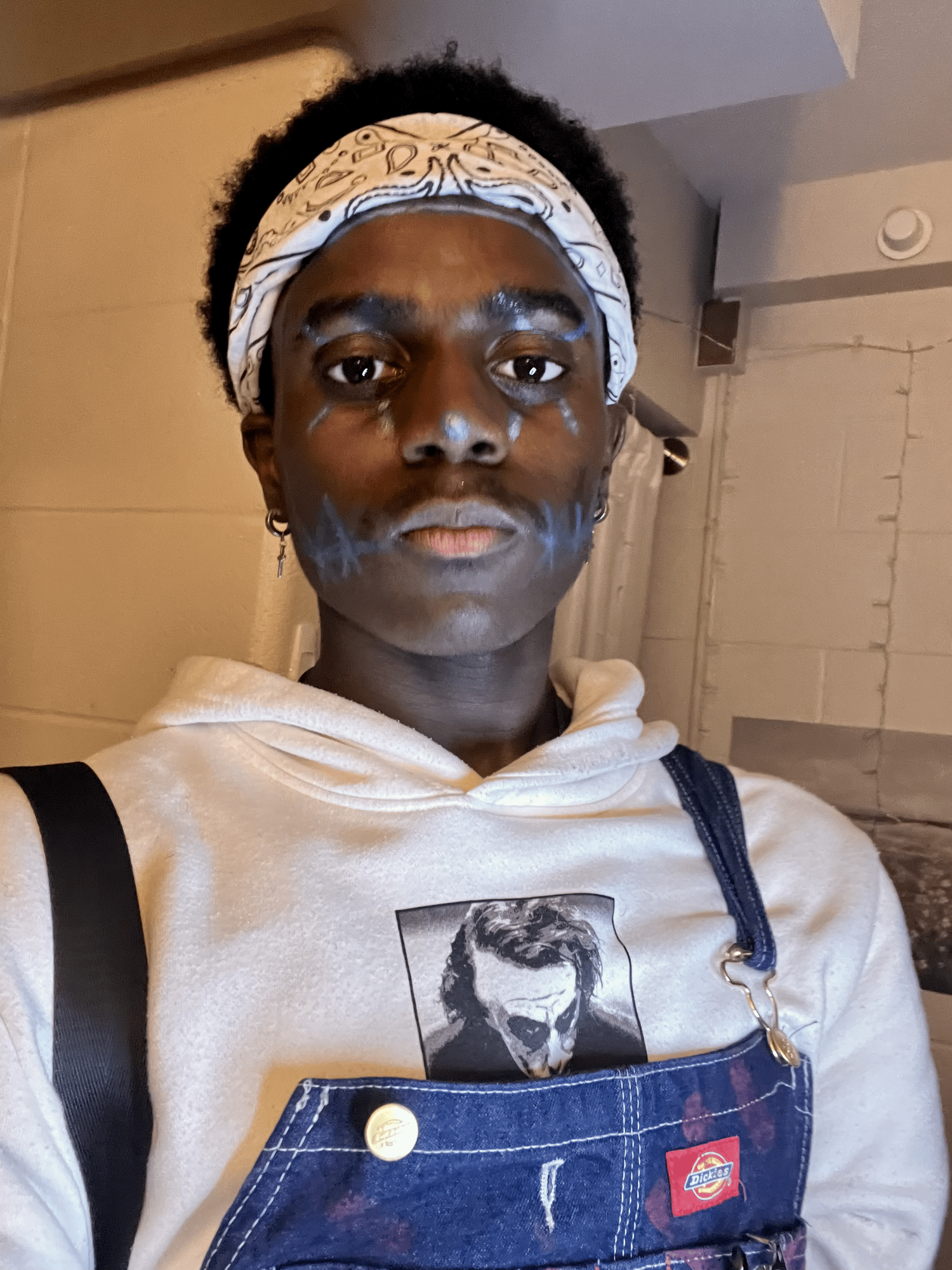 Person wearing white hoodie and denim overalls poses in series of selfie-style photos.