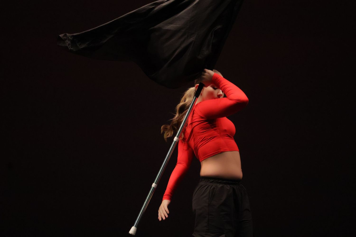 Dancers in dark lighting perform expressive movements against a black background.