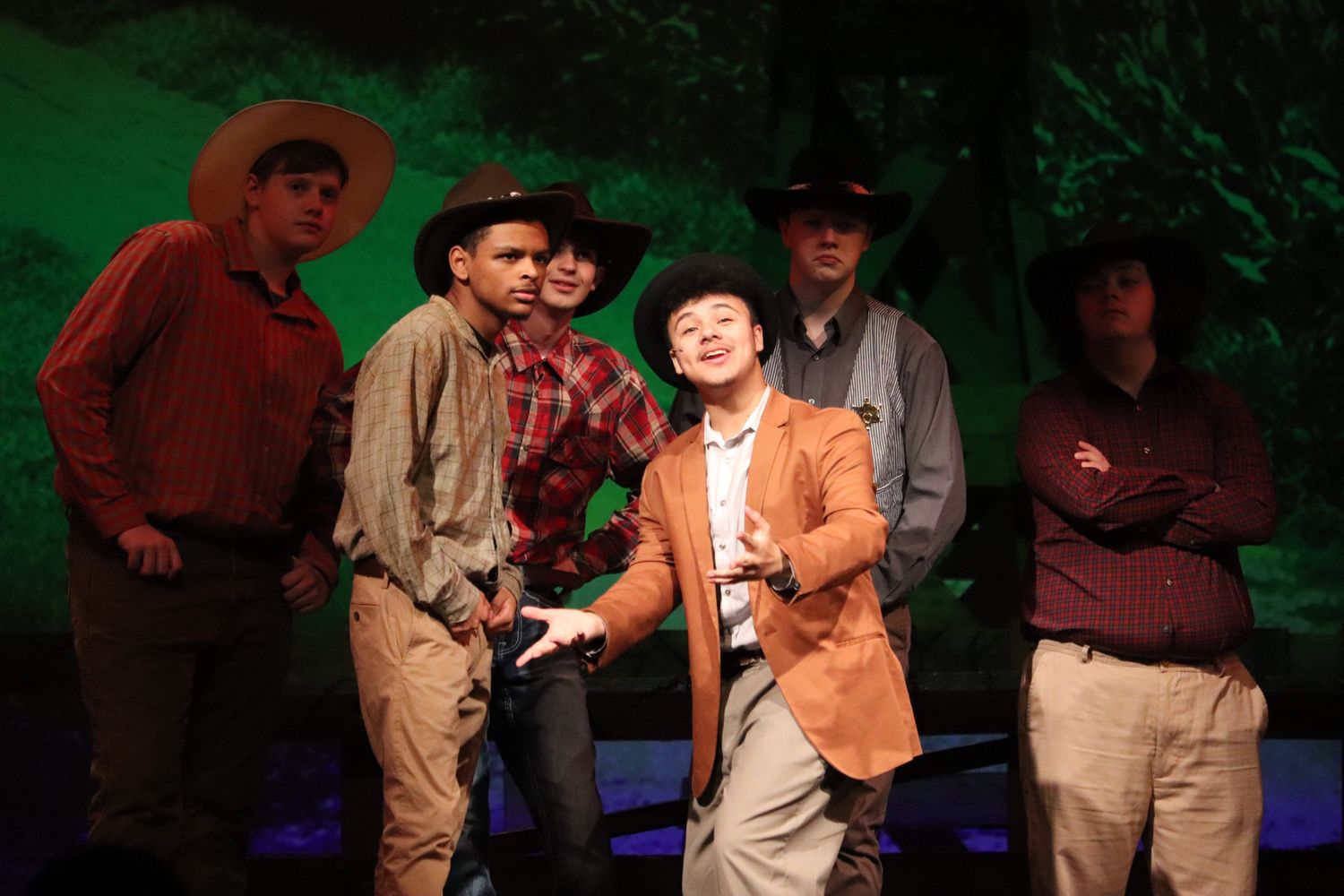 Performers in casual attire dance together on stage during a theatrical production.