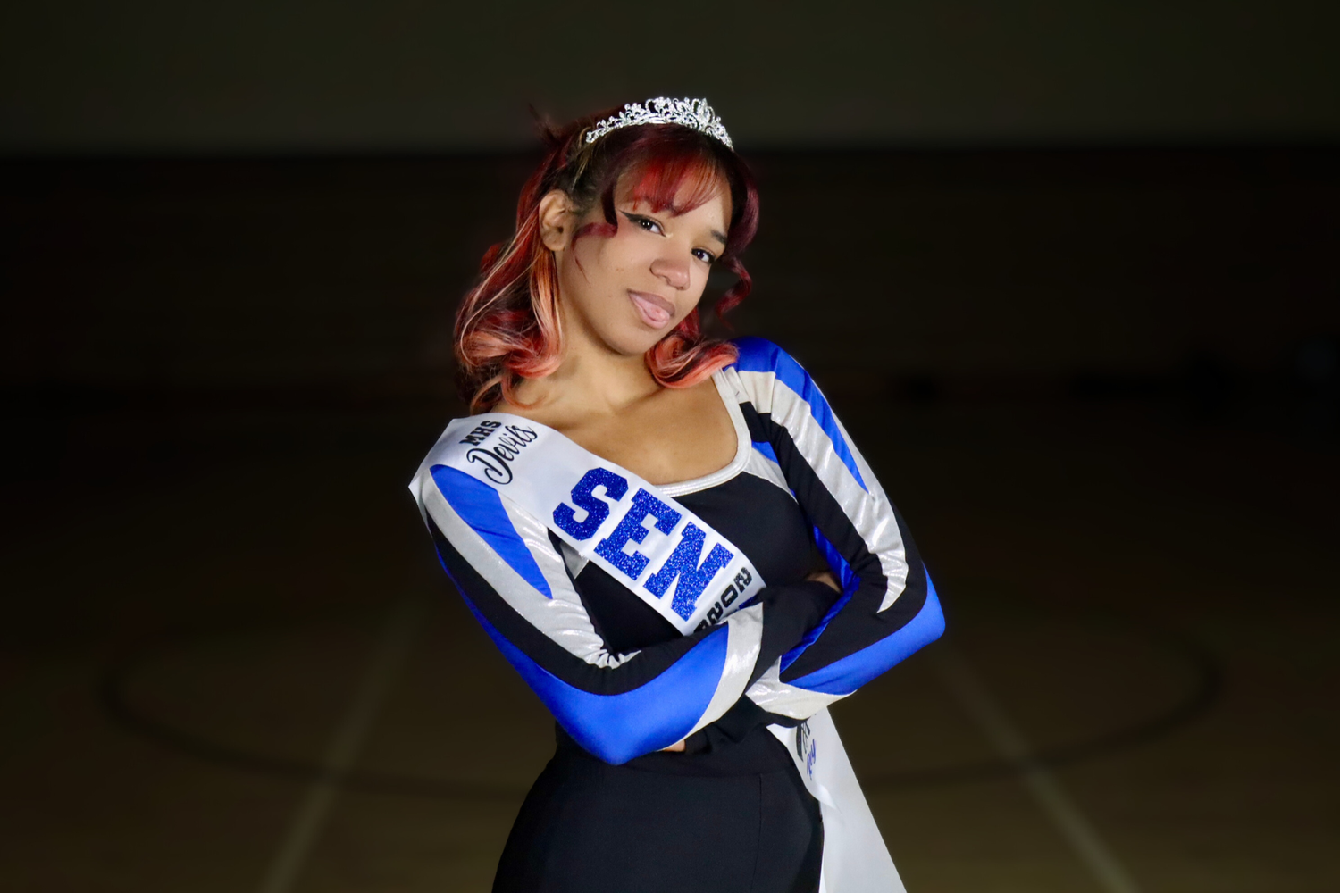Athletic dancer in blue and white costume performs dynamic movement against dark background.