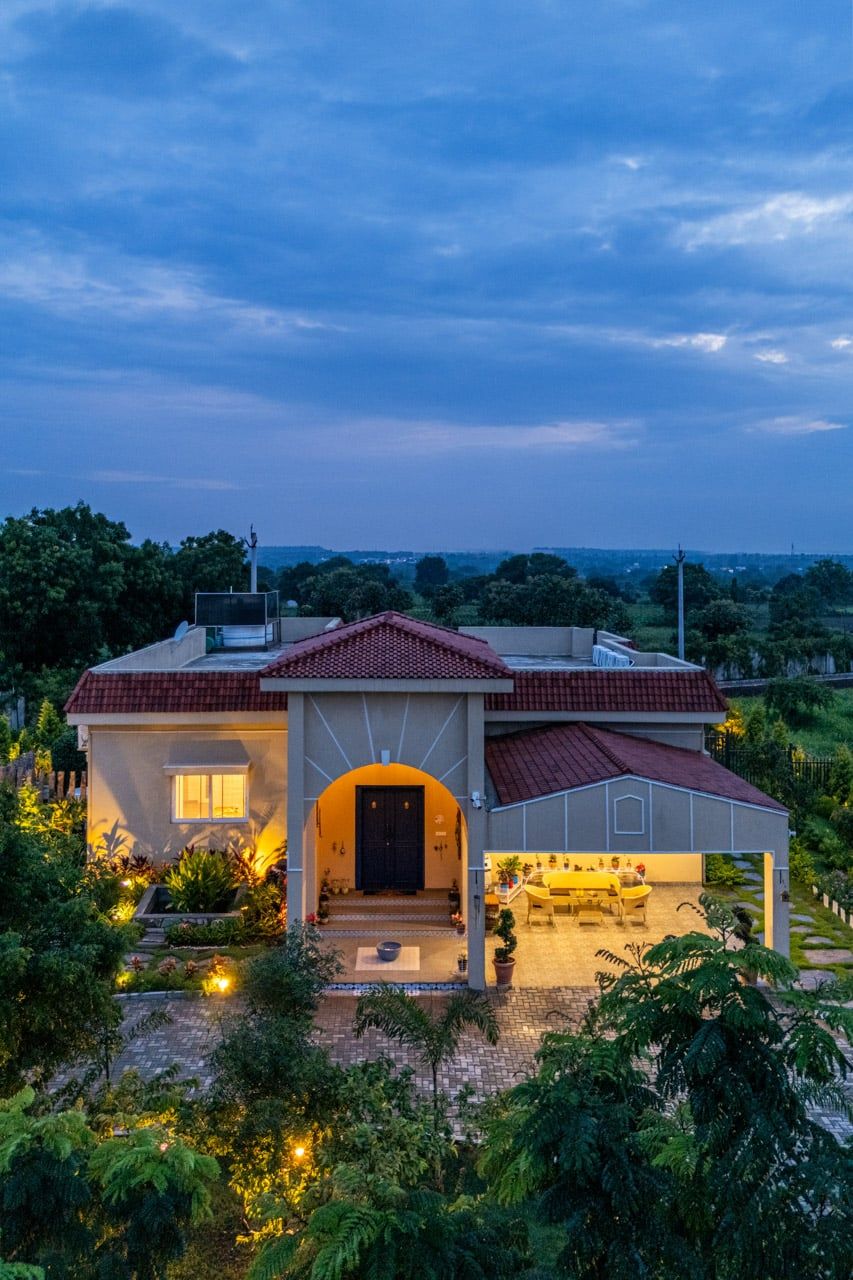 Mediterranean-style villa with warm lighting and red tile roof captured at dusk.