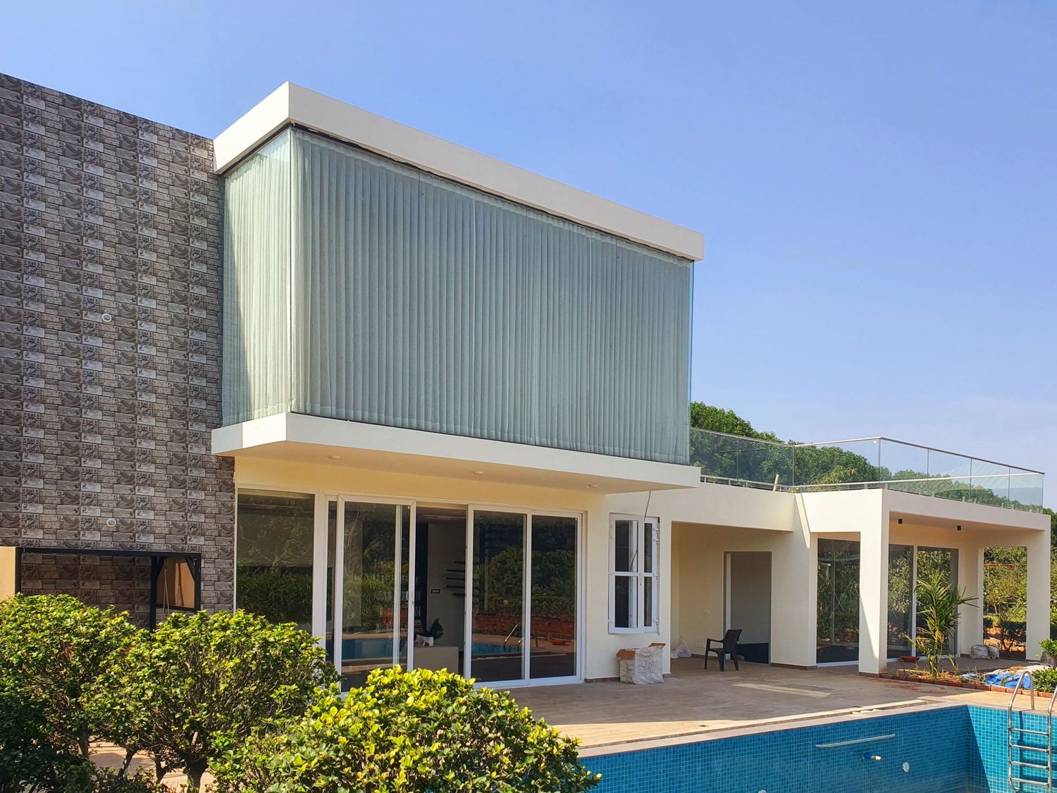 Modern white building exterior with swimming pool and landscaped garden area.