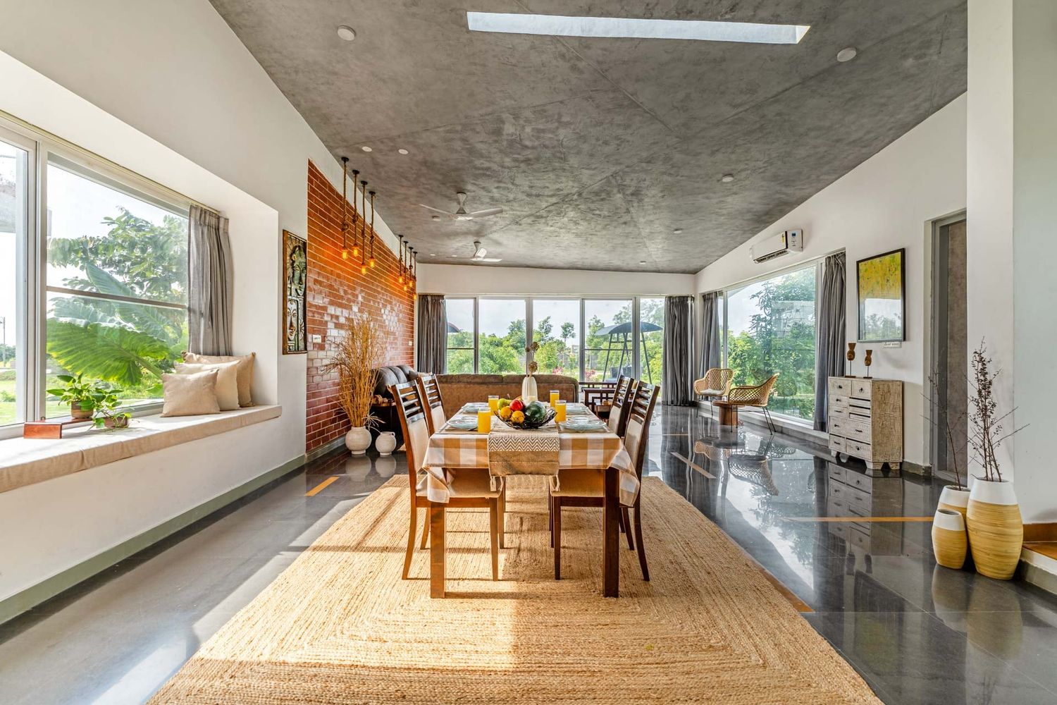 Spacious modern dining room with polished concrete floors and large windows overlooking greenery.