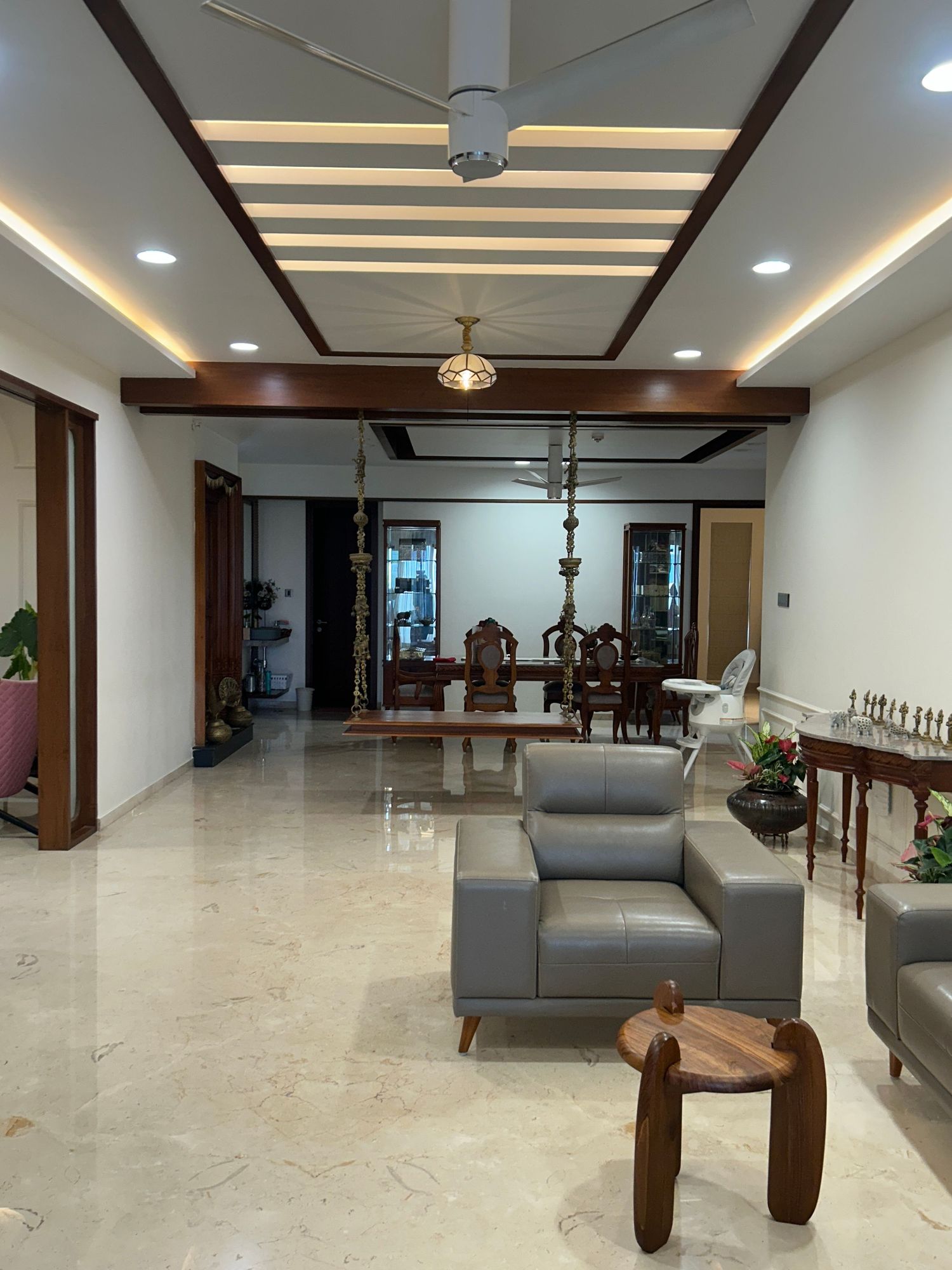 Elegant living space with marble floors, wooden ceiling beams, and contemporary gray furniture.
