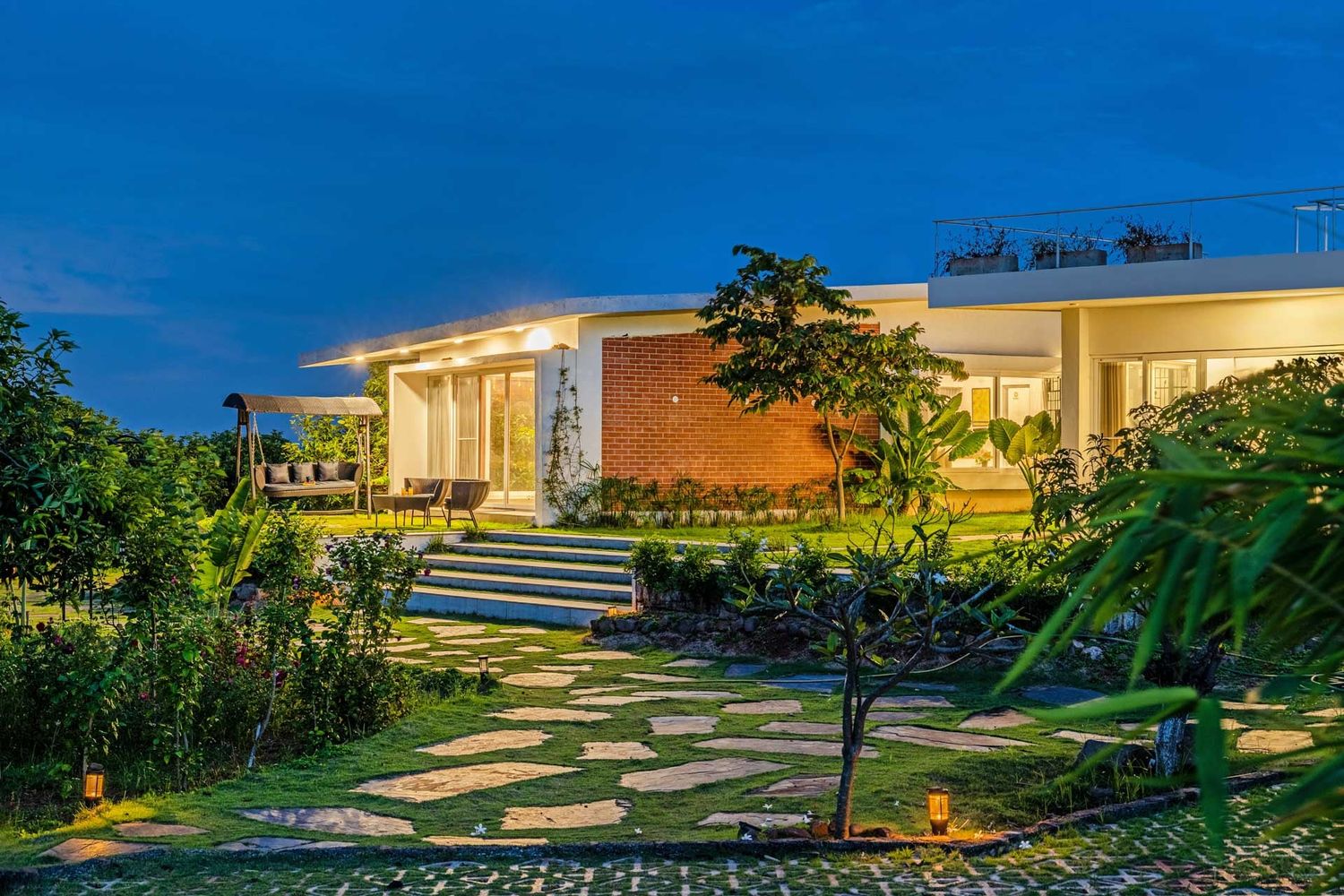 Modern house exterior with landscaped pathway and garden lighting at dusk.