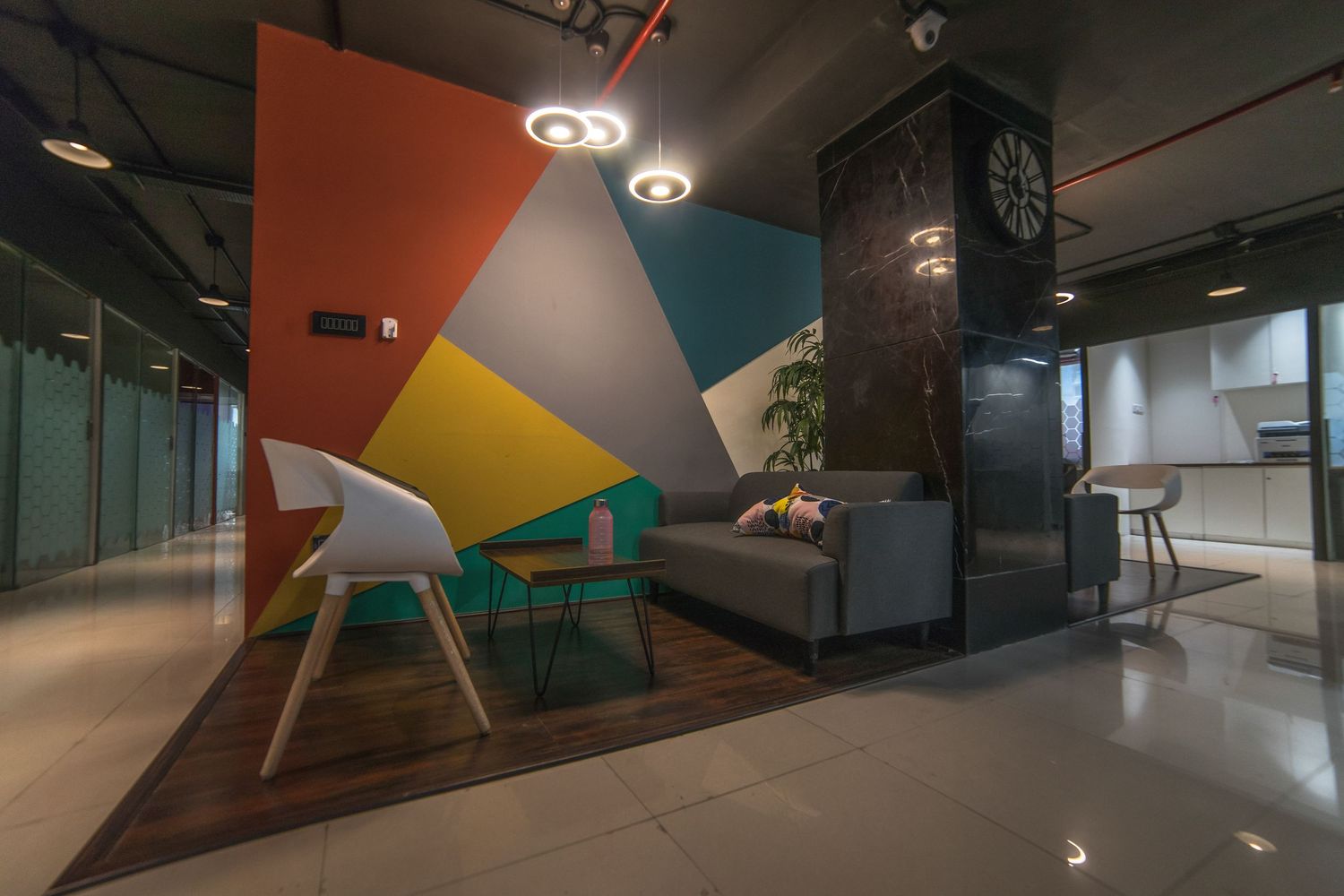Colorful geometric walls and lighting create a dynamic corridor in a modern office interior.