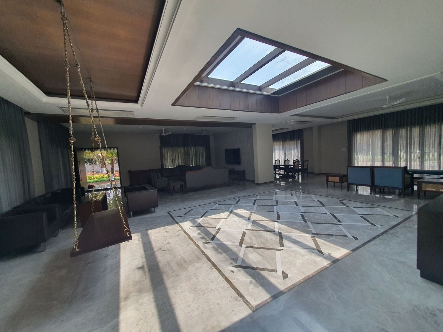 Spacious hall with skylight features marble flooring and natural light streaming through windows.