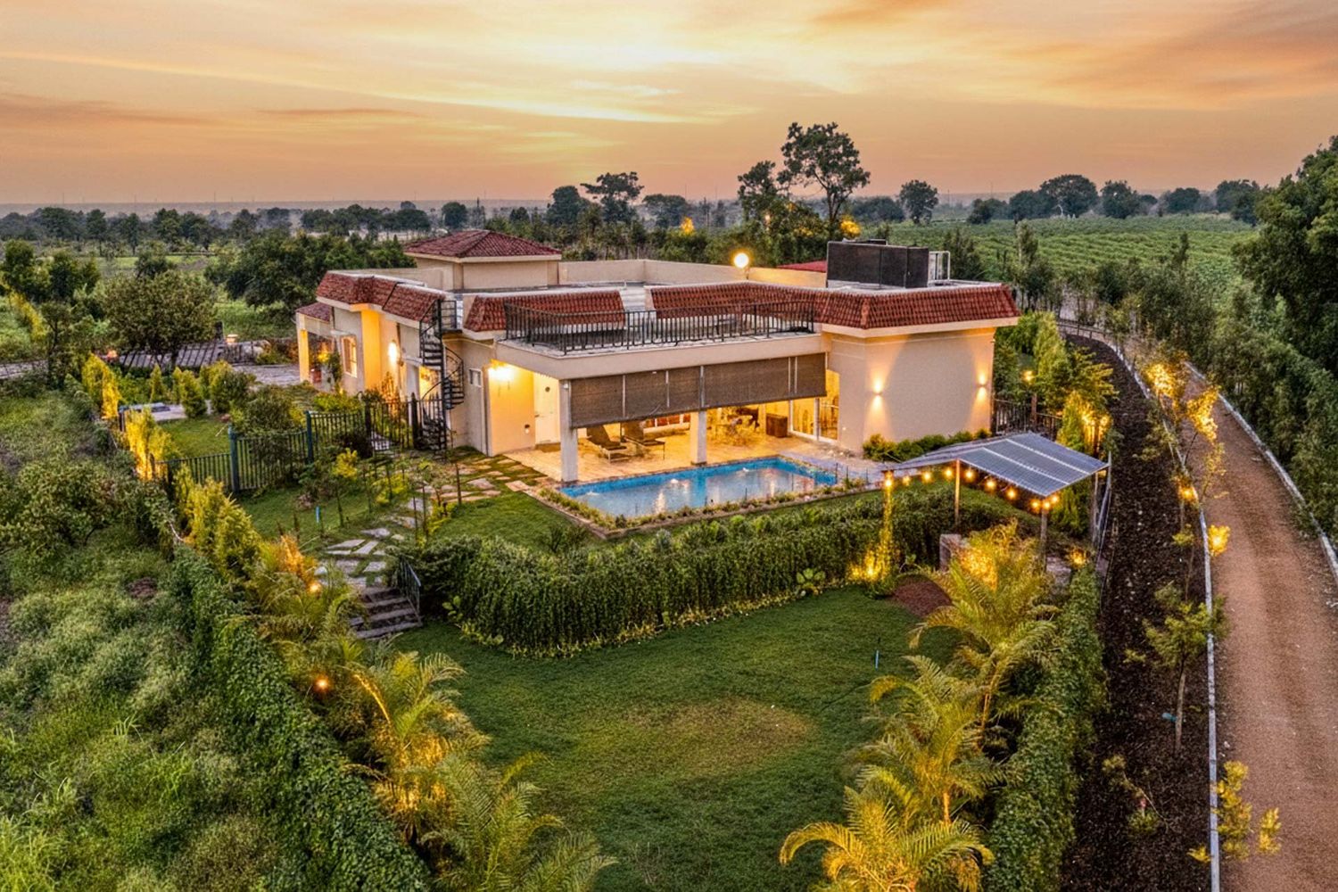Luxurious modern villa with landscaped gardens illuminated at sunset.