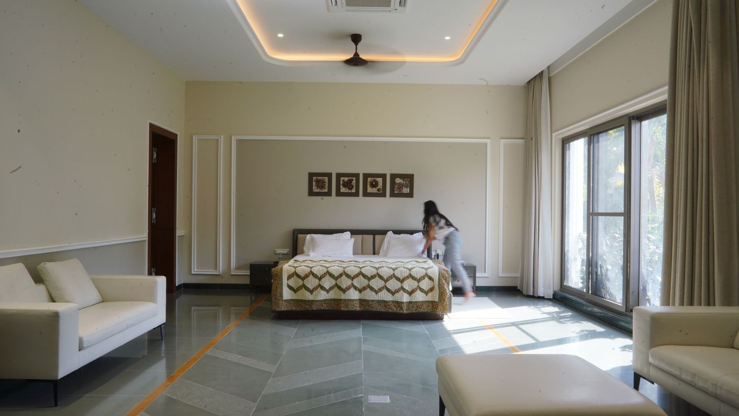 Spacious bedroom with modern decor, tray ceiling, and floor-to-ceiling windows. french panelling walls.