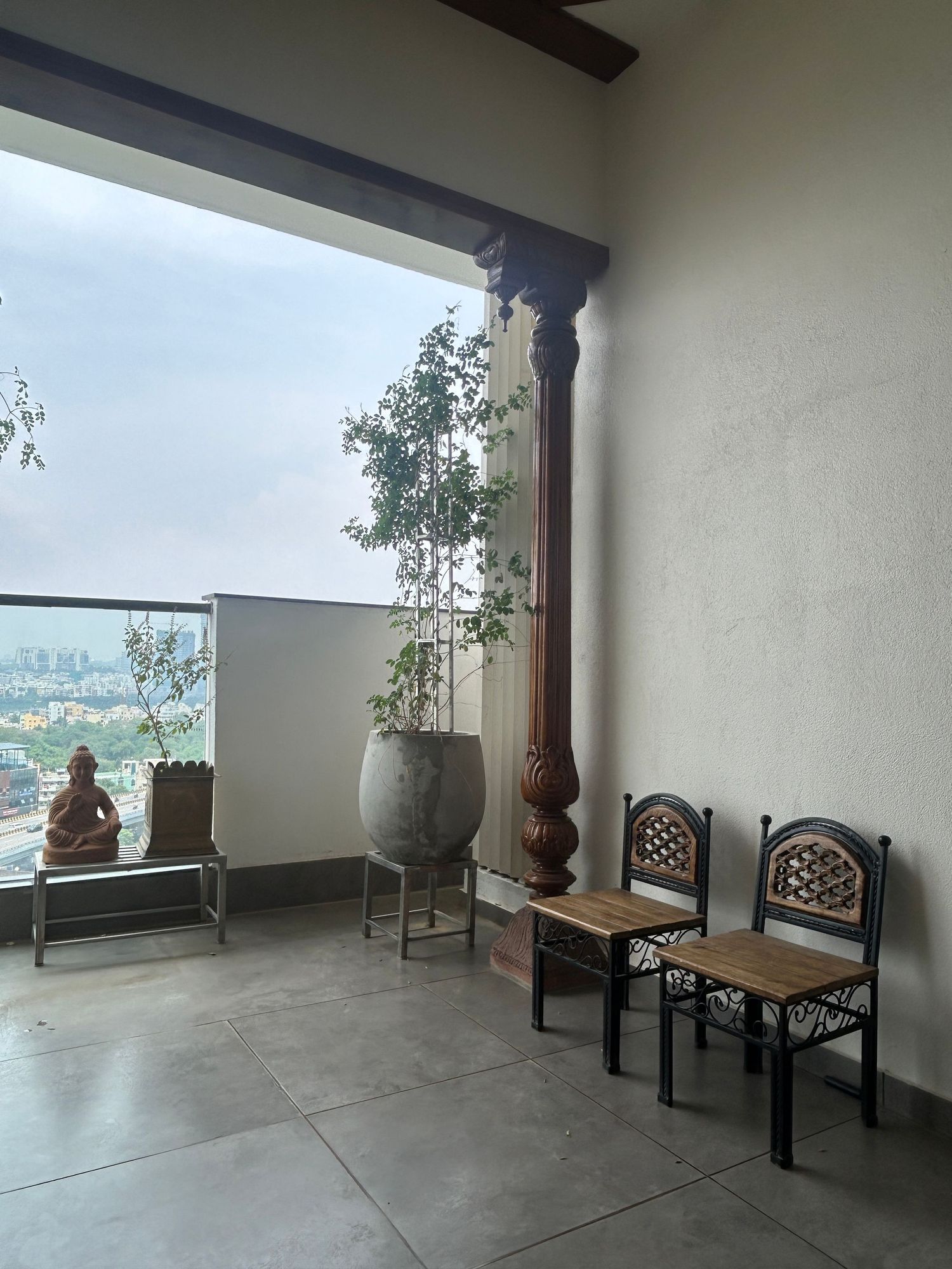 Covered terrace with traditional wooden furniture offering scenic city views.