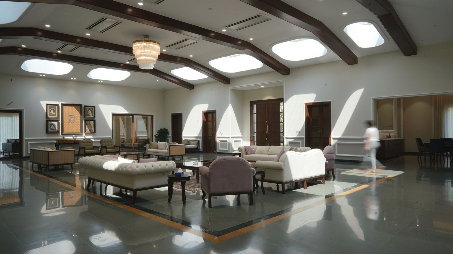 Modern conference room interior with exposed wooden beams and furniture arranged on polished floors and natural lighting through skylights.