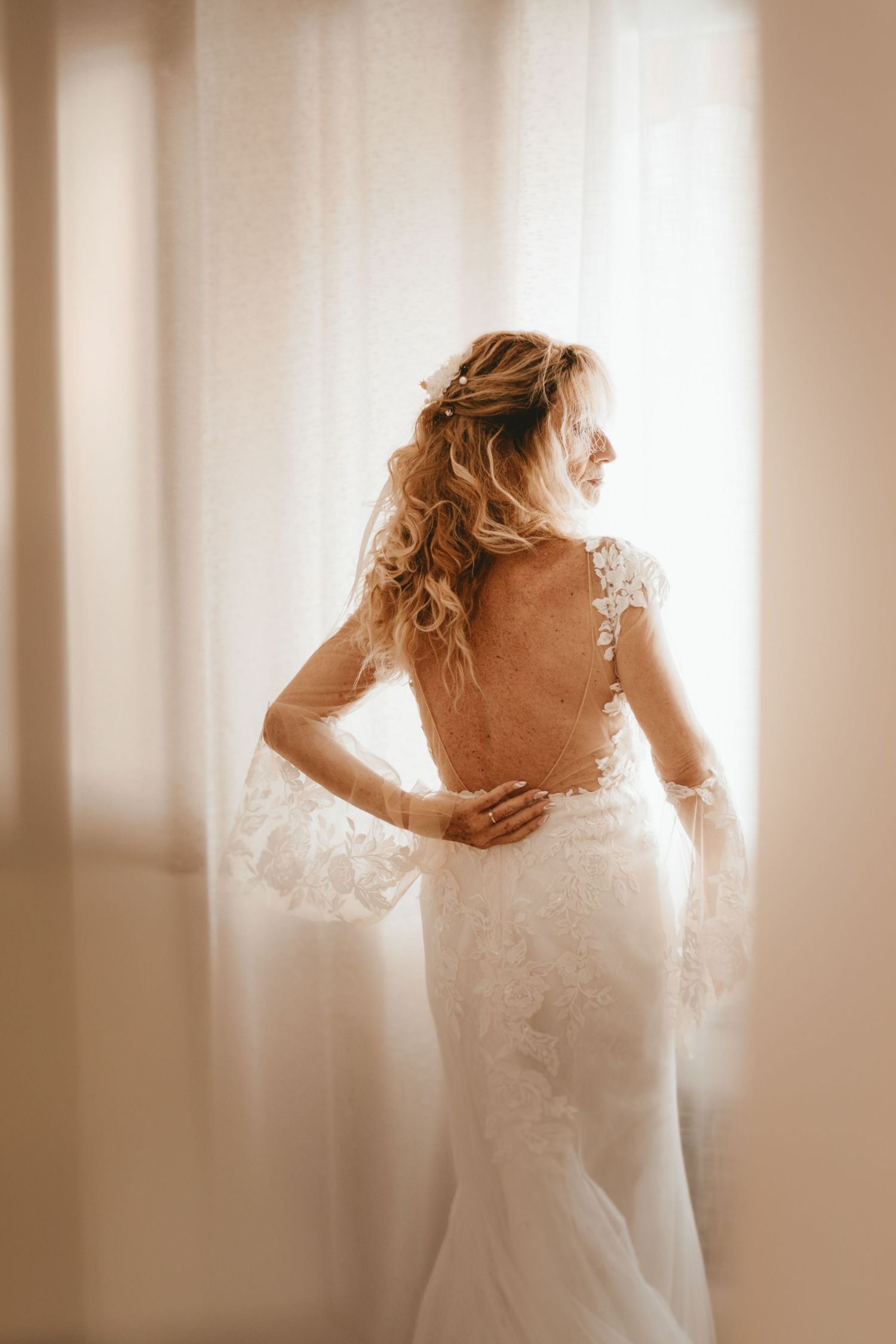 Dos de robe de mariée en dentelle, lumière naturelle chaleureuse.
