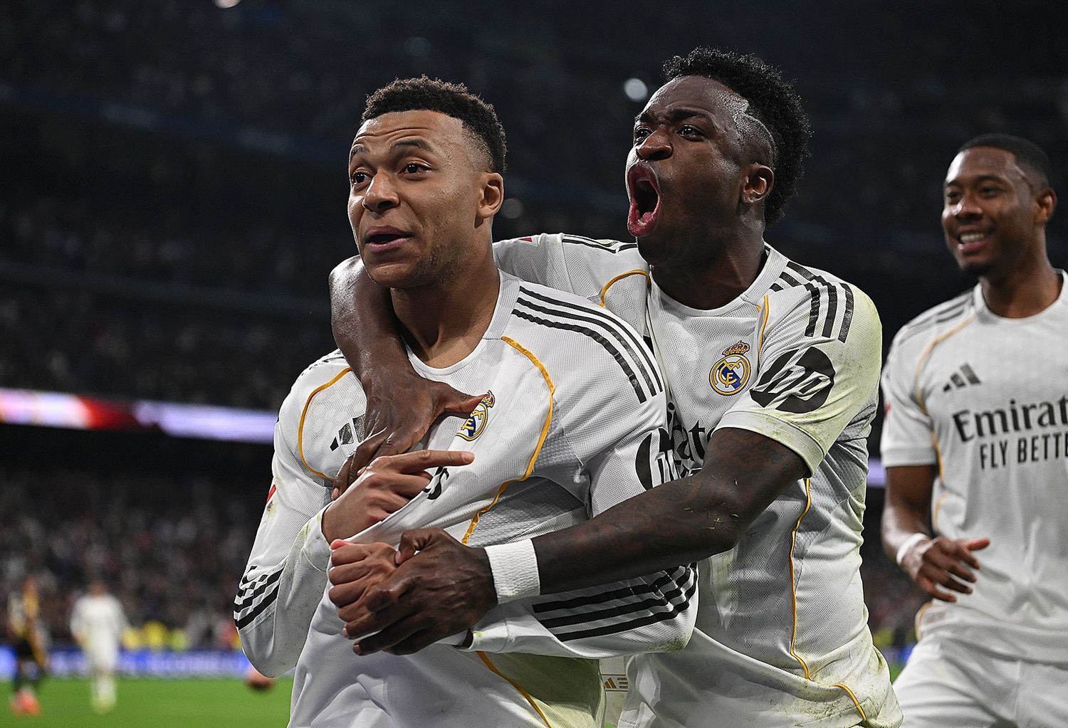 Real Madrid players celebrate a goal in white jerseys at Santiago Bernabeu stadium during a Champions League match.