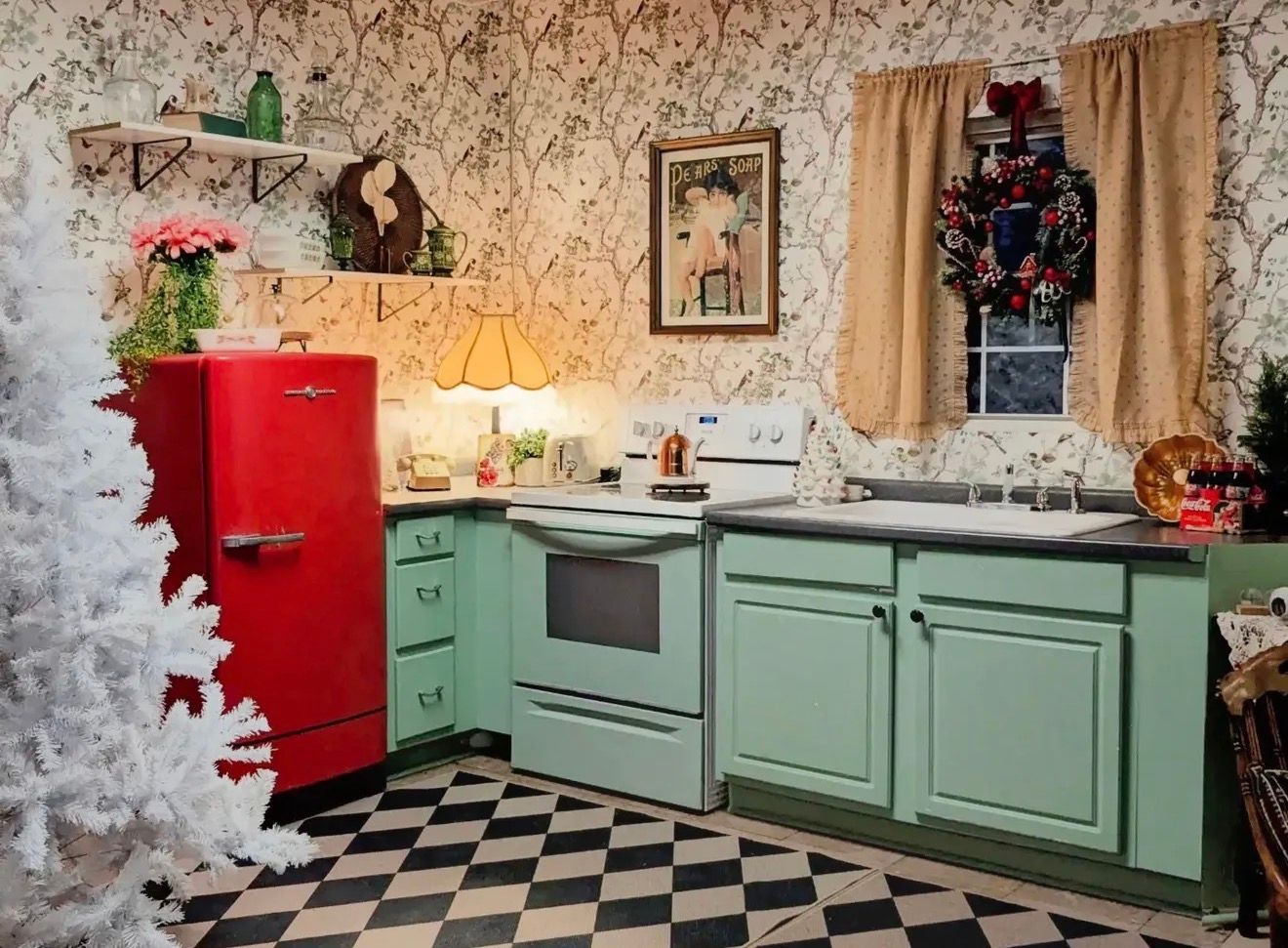 Retro kitchen with mint green cabinets, red vintage fridge, checkered floor, and festive Christmas decorations.