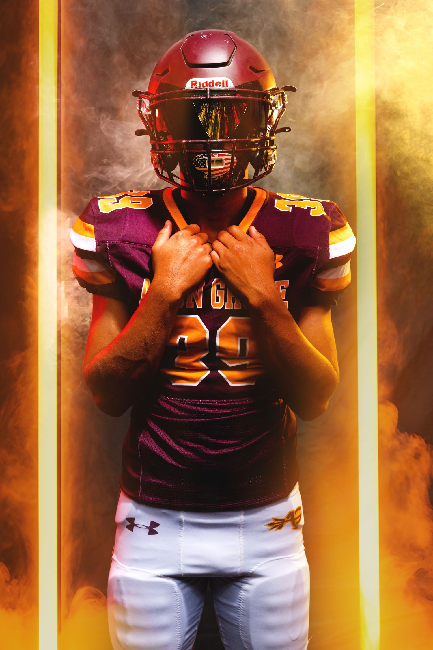 A football player in maroon and gold uniform with Riddell helmet poses dramatically against a fiery smoke background.