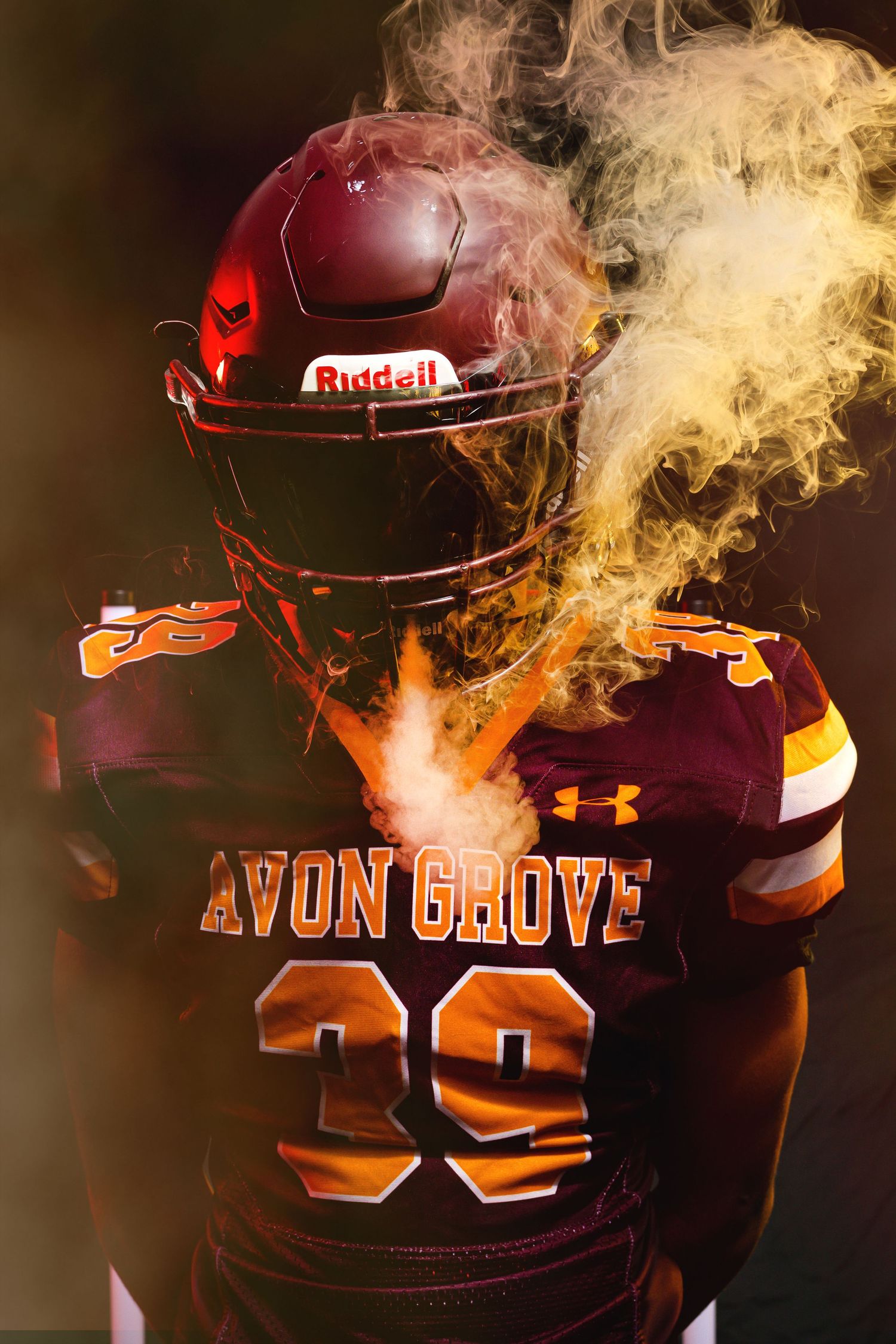 Avon Grove #39 football player surrounded by golden smoke in dramatic dark studio shot.