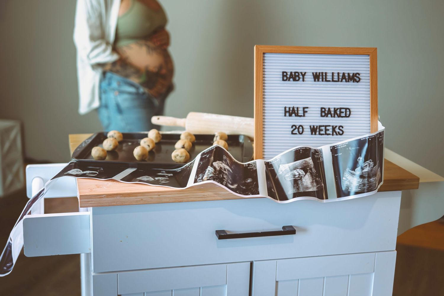 Half baked 20 weeks pregnancy announcement sign with ultrasound photos and cookie dough.