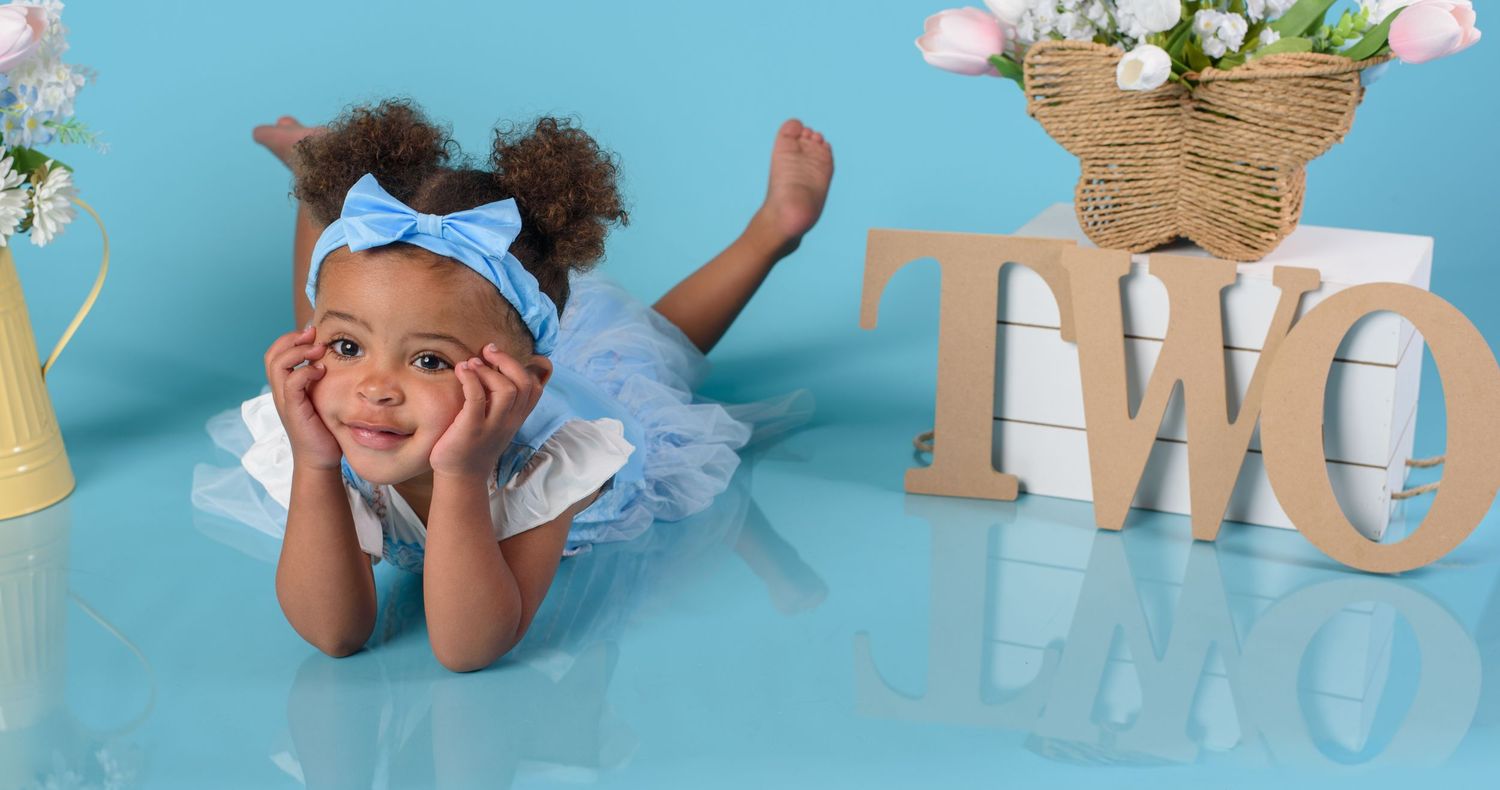 Toddler girl in blue tutu dress poses with TWO sign for second birthday photo session.