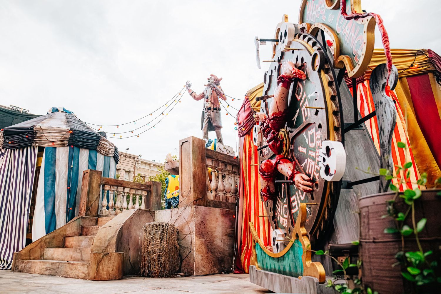 Colorful pirate-themed theme park attraction with large ship wheel decor and costumed performer on wooden stage.