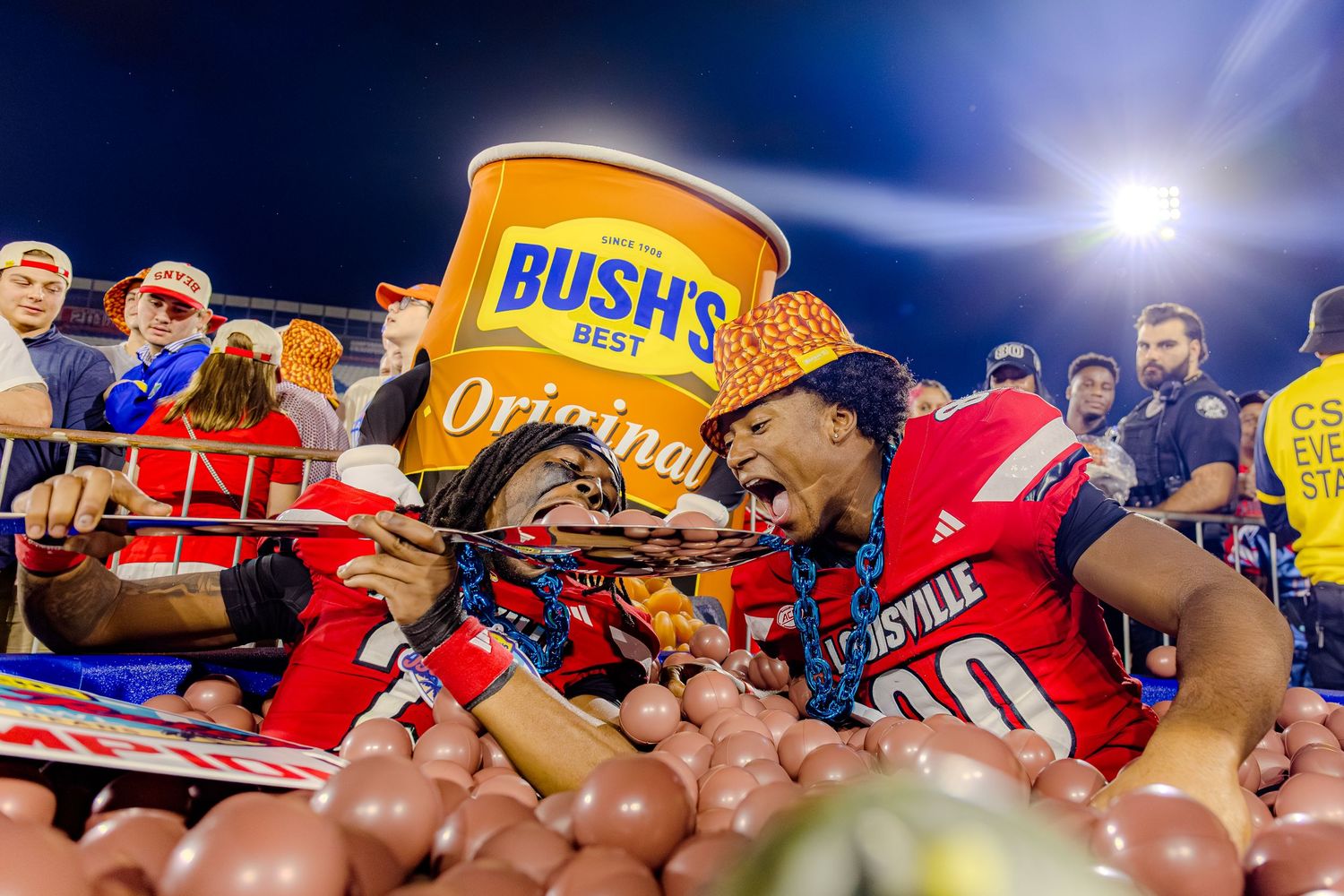College athlete celebrates with a Bush's beans prop during a nighttime sporting event.