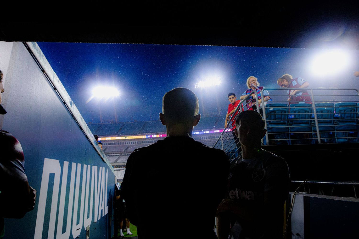 Silhouetted figures against stadium lights during nighttime sporting event.